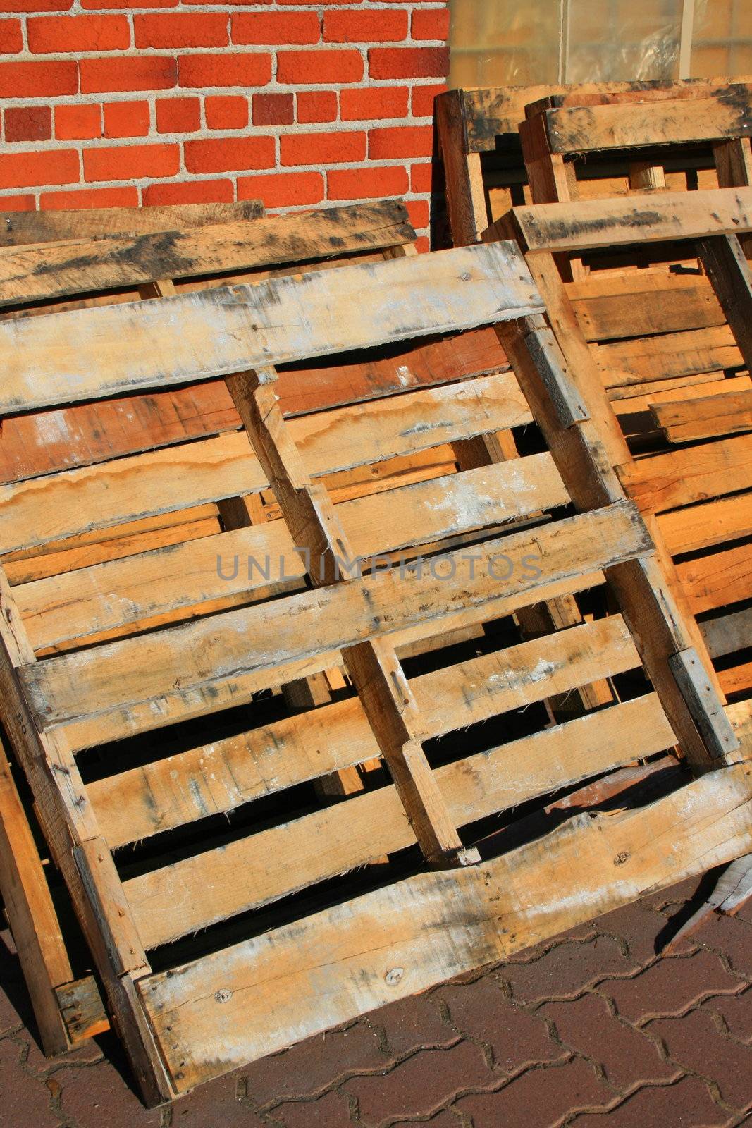 Wooden pallets close up next to a brickwall.
