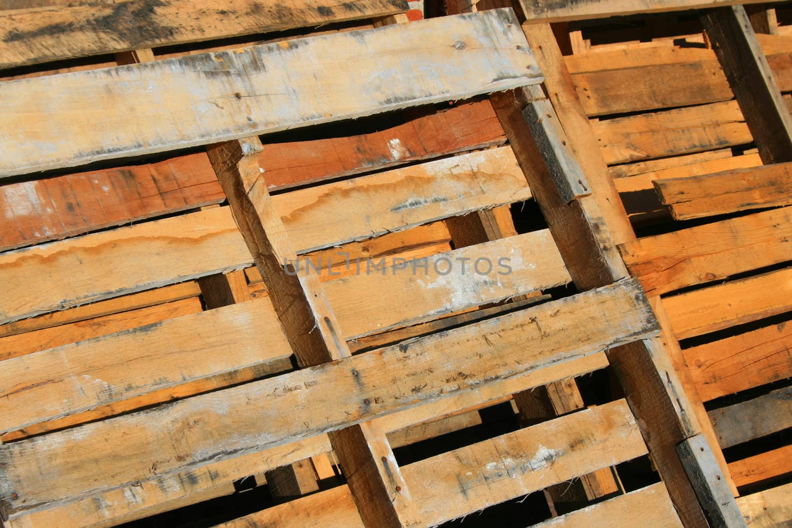 Wooden pallets close up next to a brickwall.
