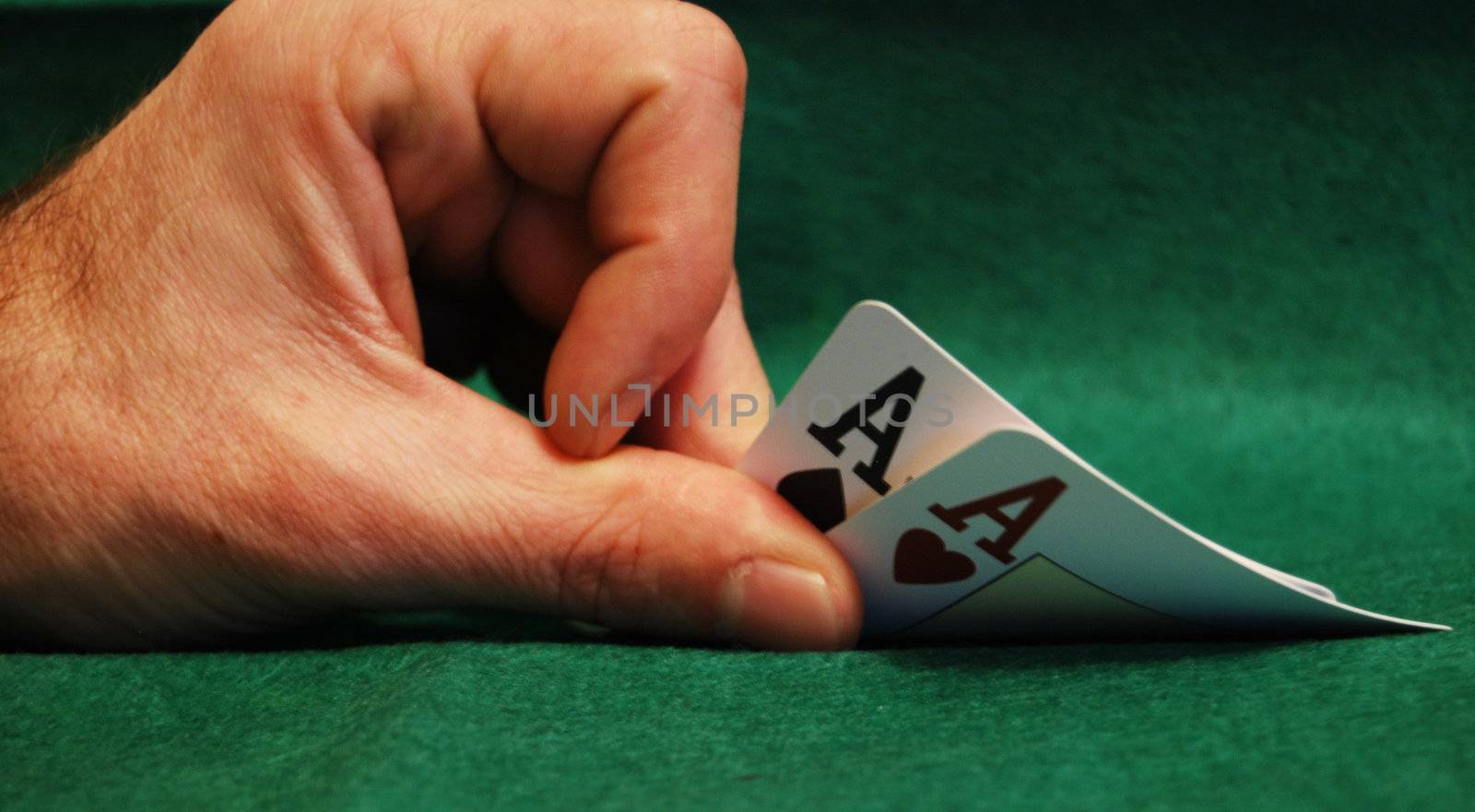 Gambler hand revealing ace of hearts on green table