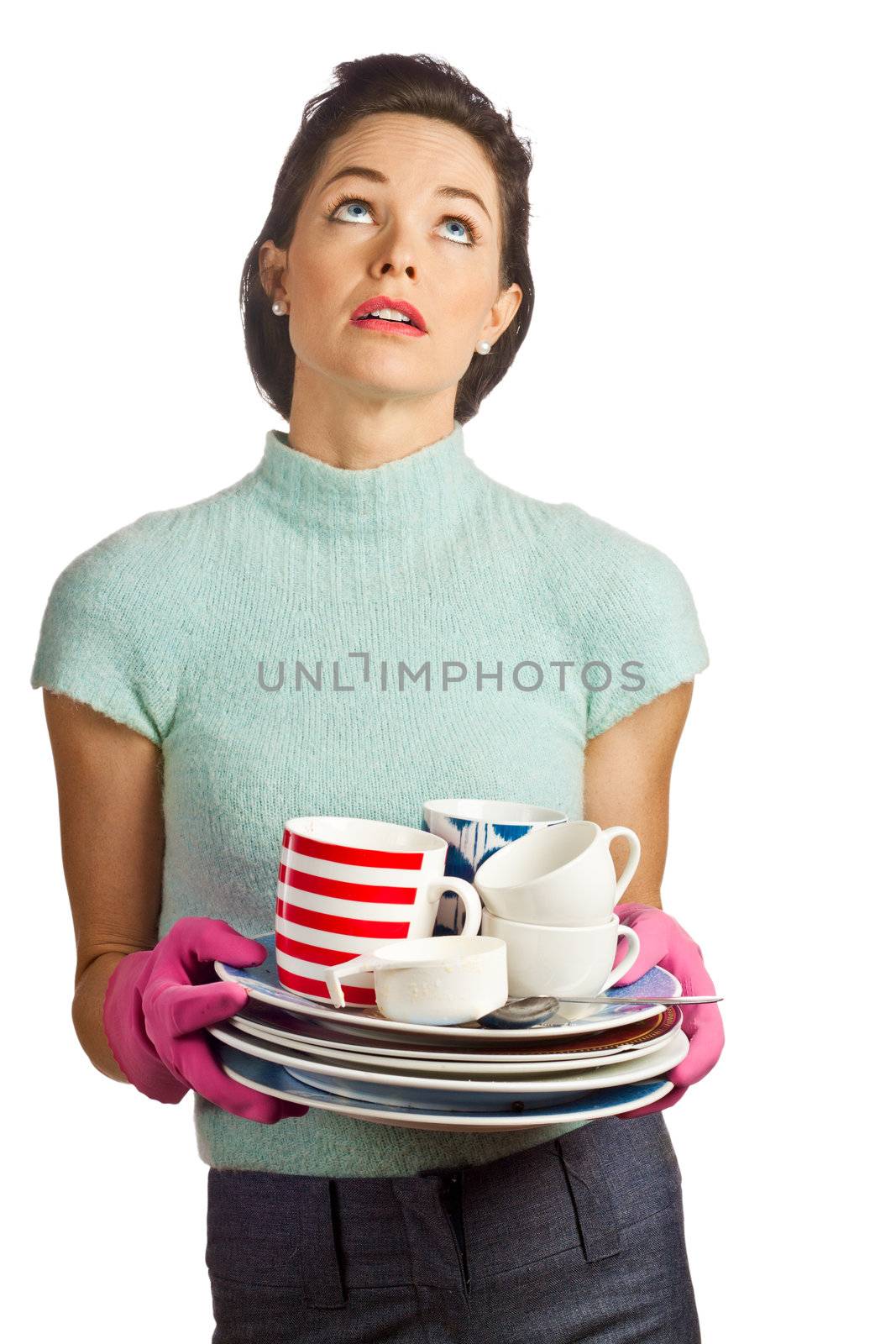 Portrait of a young beautiful housewife holding a pile of dirty dishes and looking fed up. Isolated over white.
