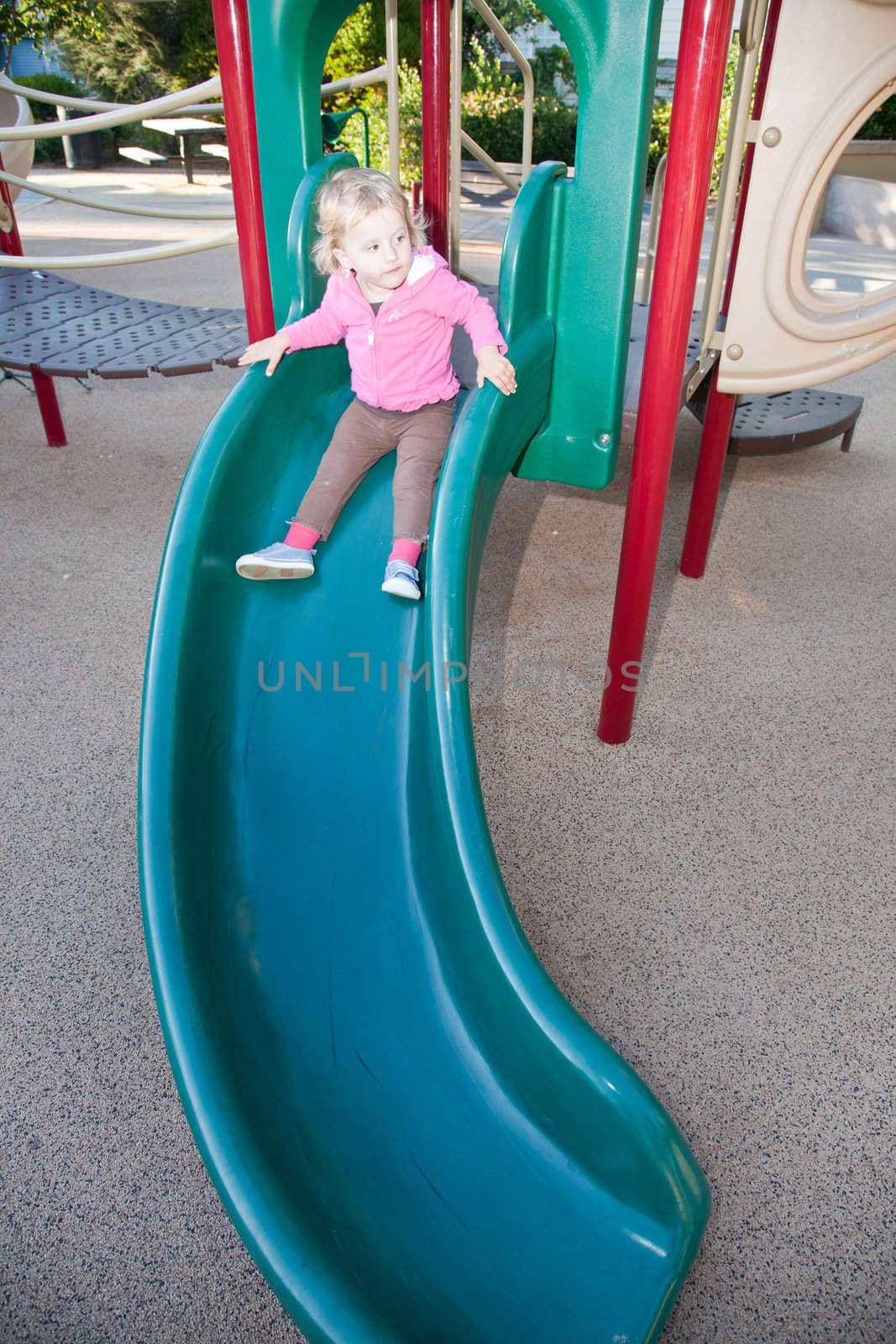 Cute little Caucasian girl having fun on playground in a park.