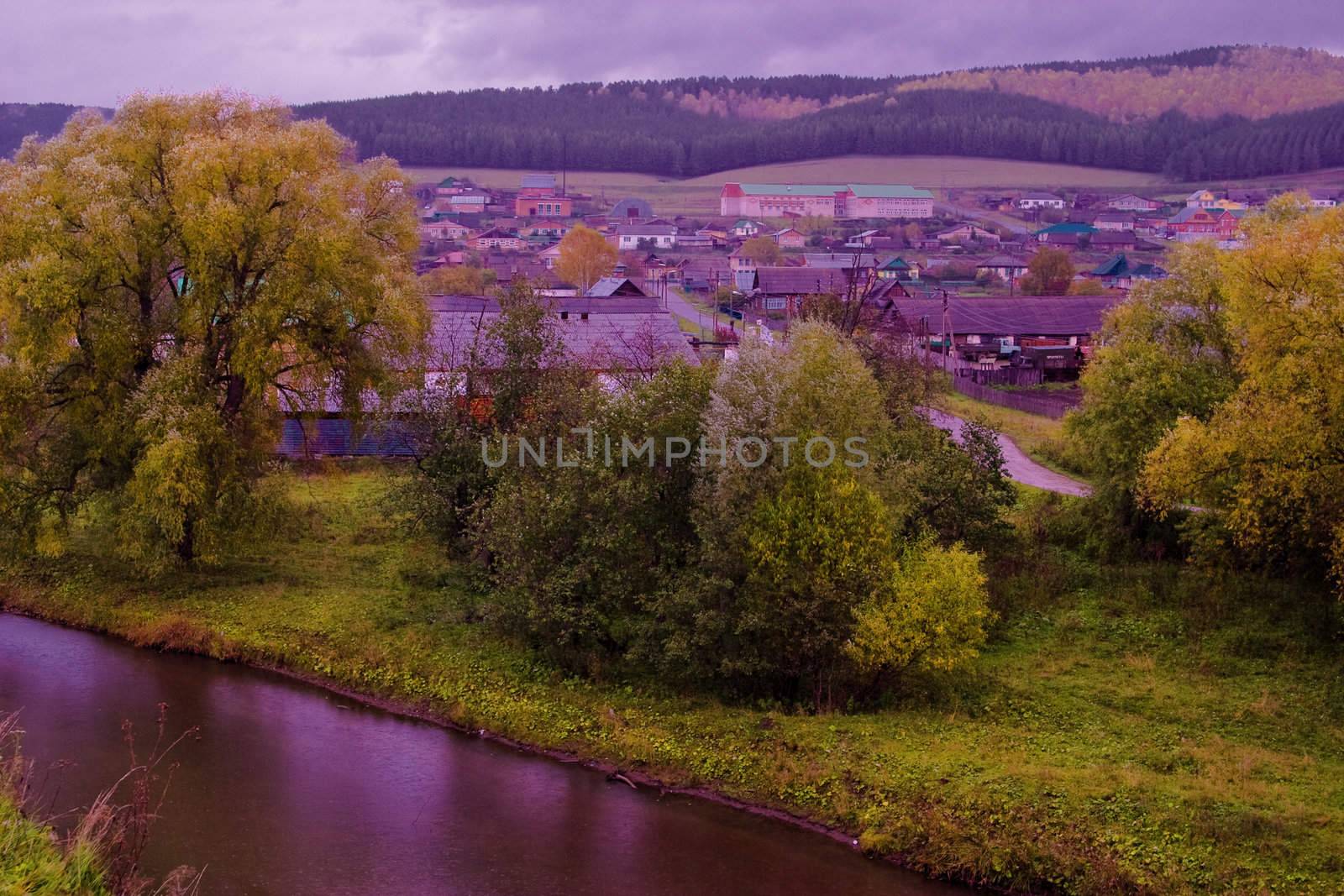 Autumn landscape: the quiet provincial town situated among the picturesque hills. Shooting in rainy weather. Low contrast emphasizes the autumn colors