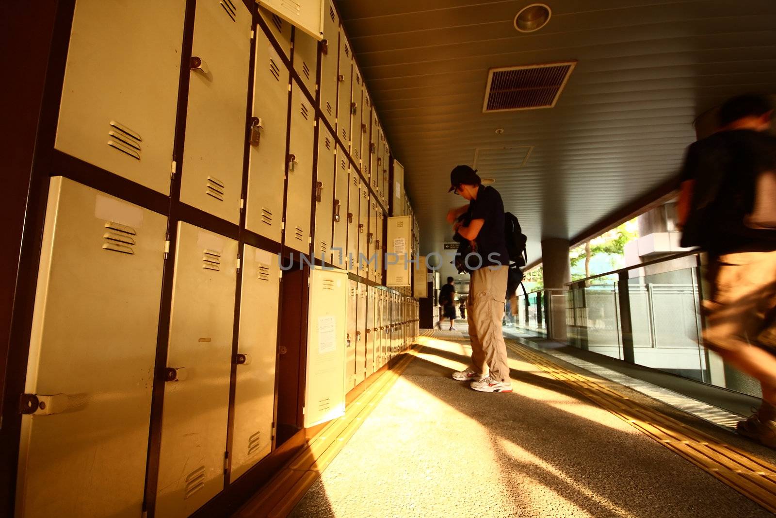 asian student taking books from locker at school