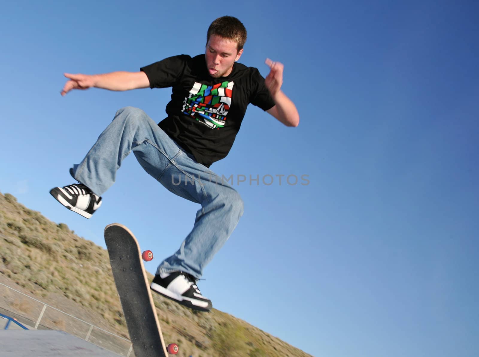 A young skater jumping over a ramp in a park
