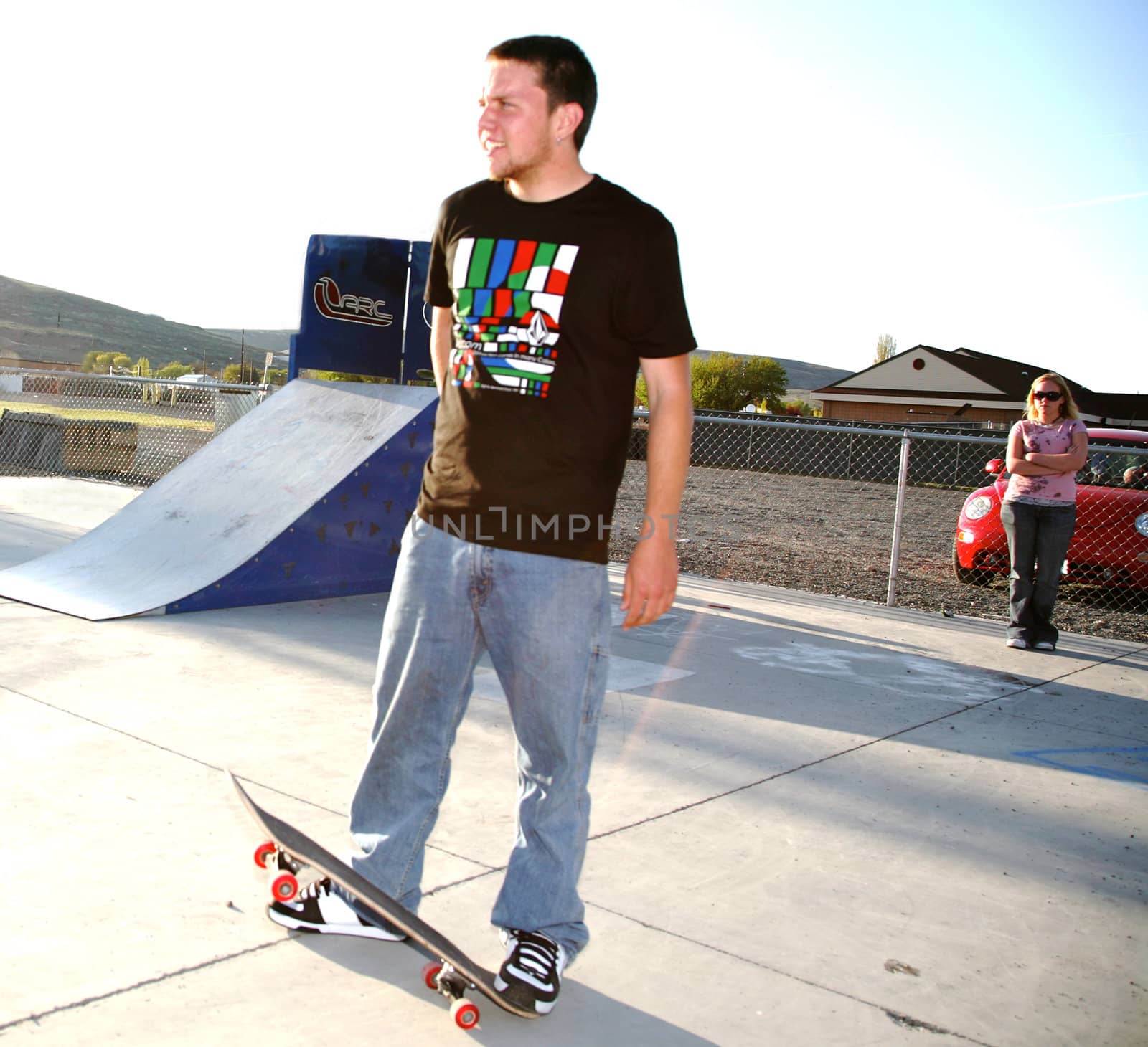 A man at a skater park and a girl in the background 
