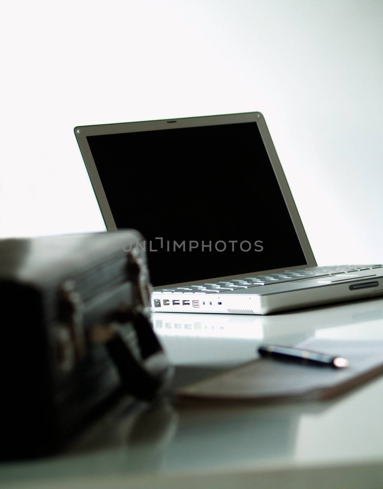 A black leather suitcase, a calender and a laptop
