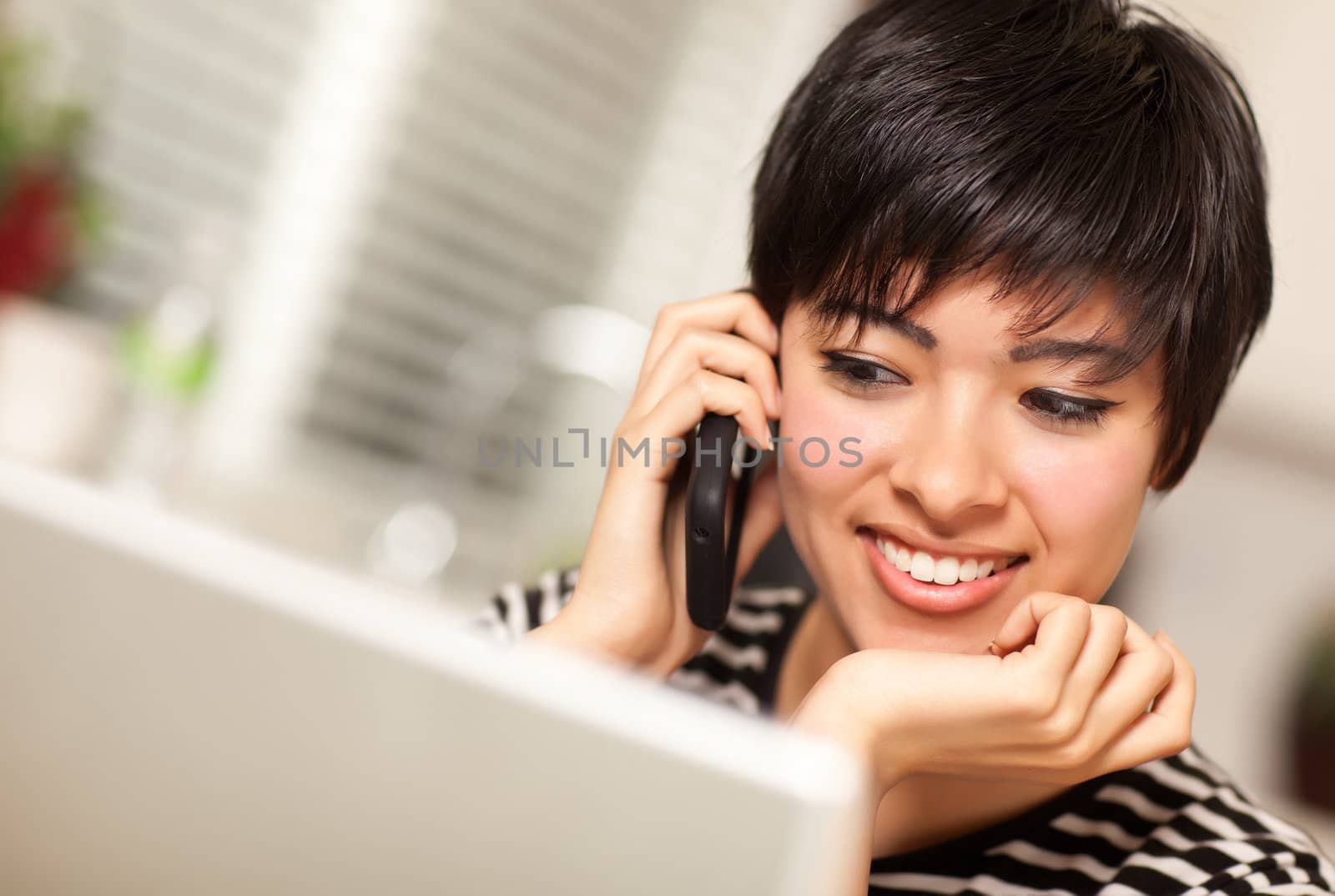 Pretty Smiling Multiethnic Woman with Cell Phone Using Laptop by Feverpitched