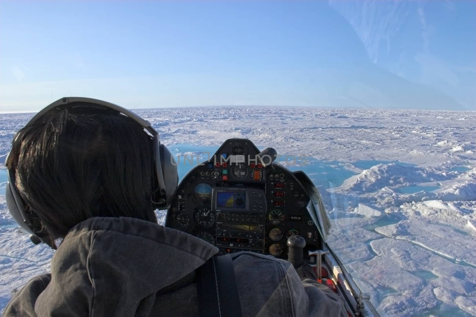 Pilot of a small airplane flies over ice shields of the Arctic Ocean above ice and slow on the background of blue sky