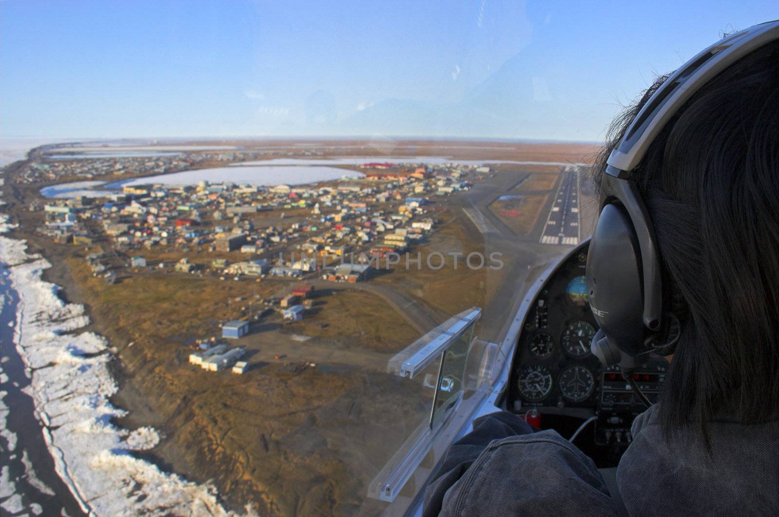 Pilot of a small airplane flies over Arctic Ocean shore and is getting ready to land on the airstrip of the whaling village of Barrow, the north most point of the USA 