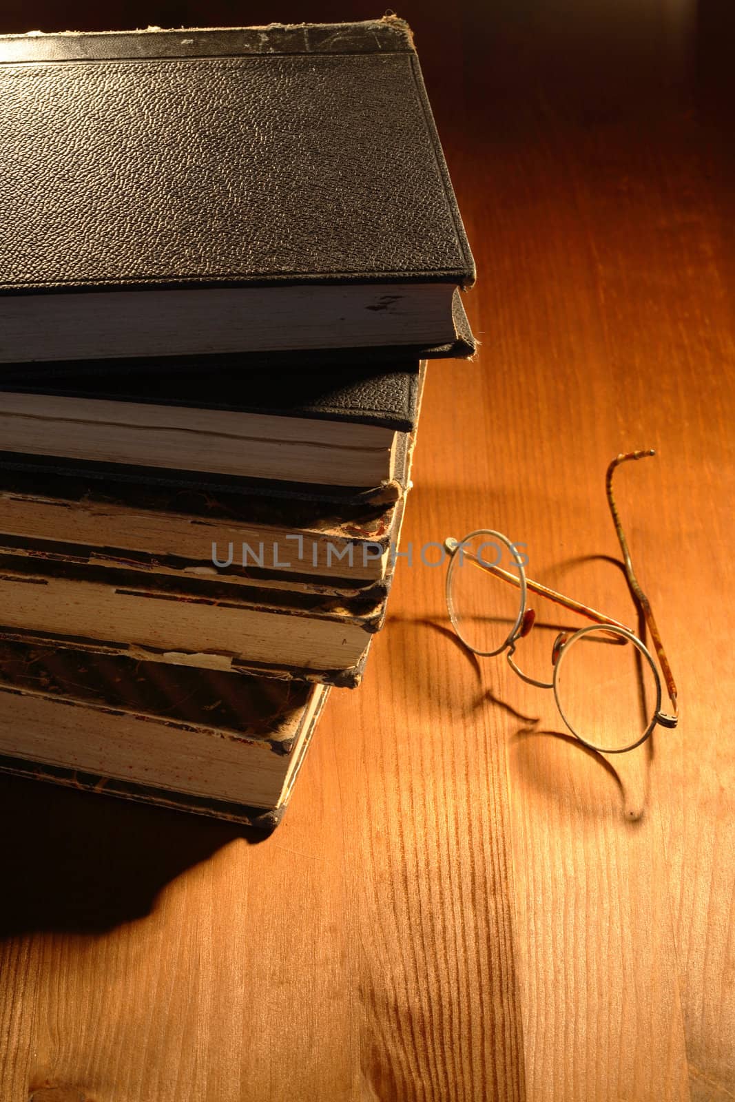 Very old eyeglasses near books lying on nice wooden background