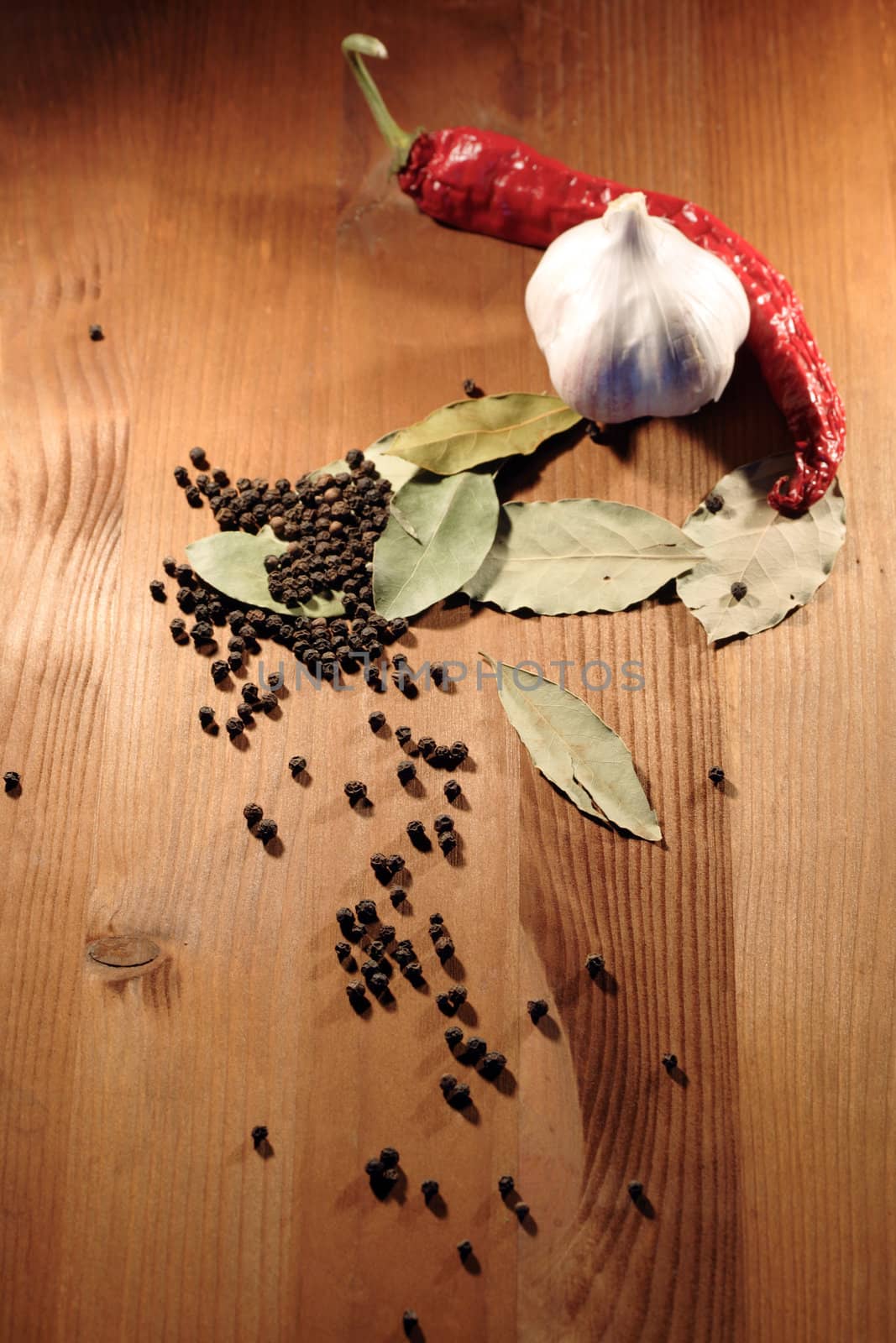 Bay leaves, head of garlic and peppercorns on wooden background