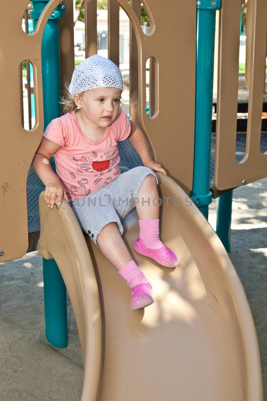 Cute little European toddler girl having fun at the playground in the park.