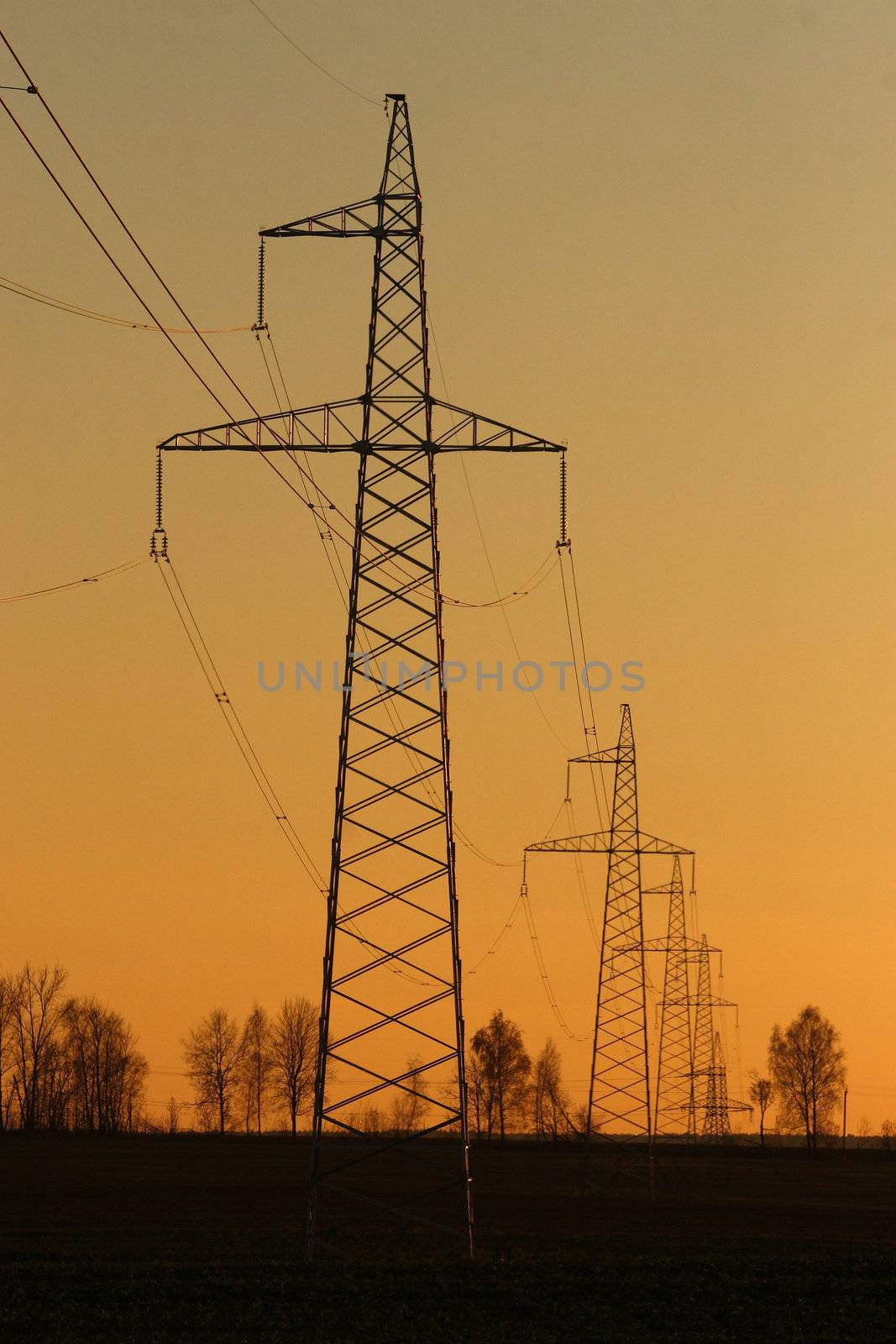 Sun setting behind a row of electricity pylons