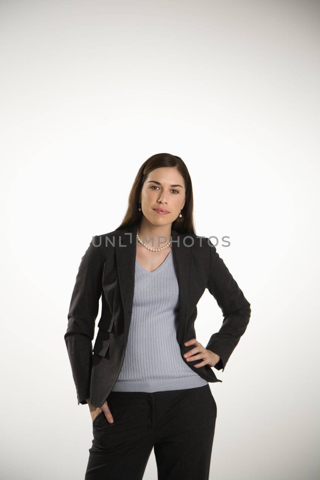 Portrait of Caucasian mid adult professional business woman standing with hand on hip looking at viewer.