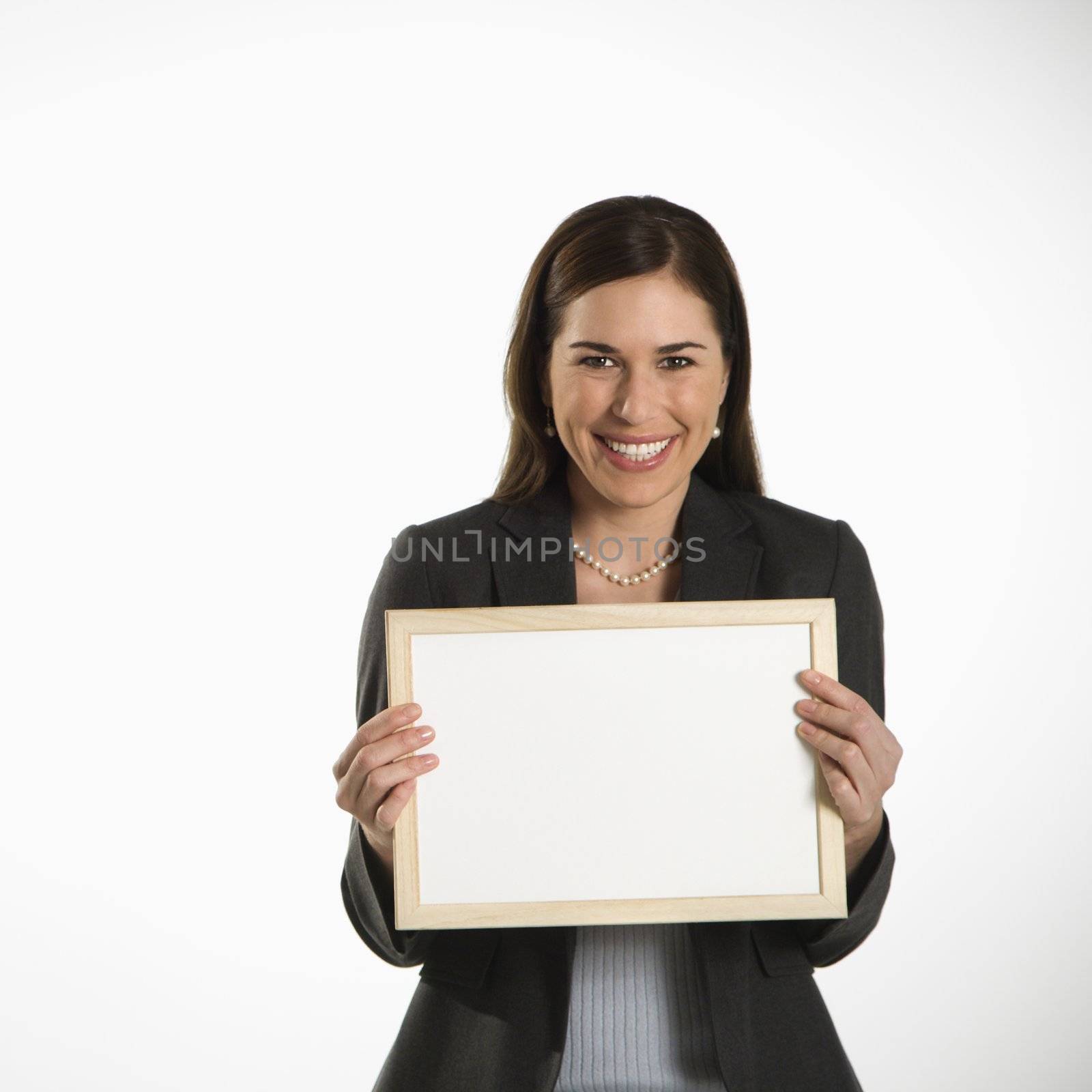 Portrait of Caucasian mid adult professional business woman holding blank sign looking at viewer and smiling.