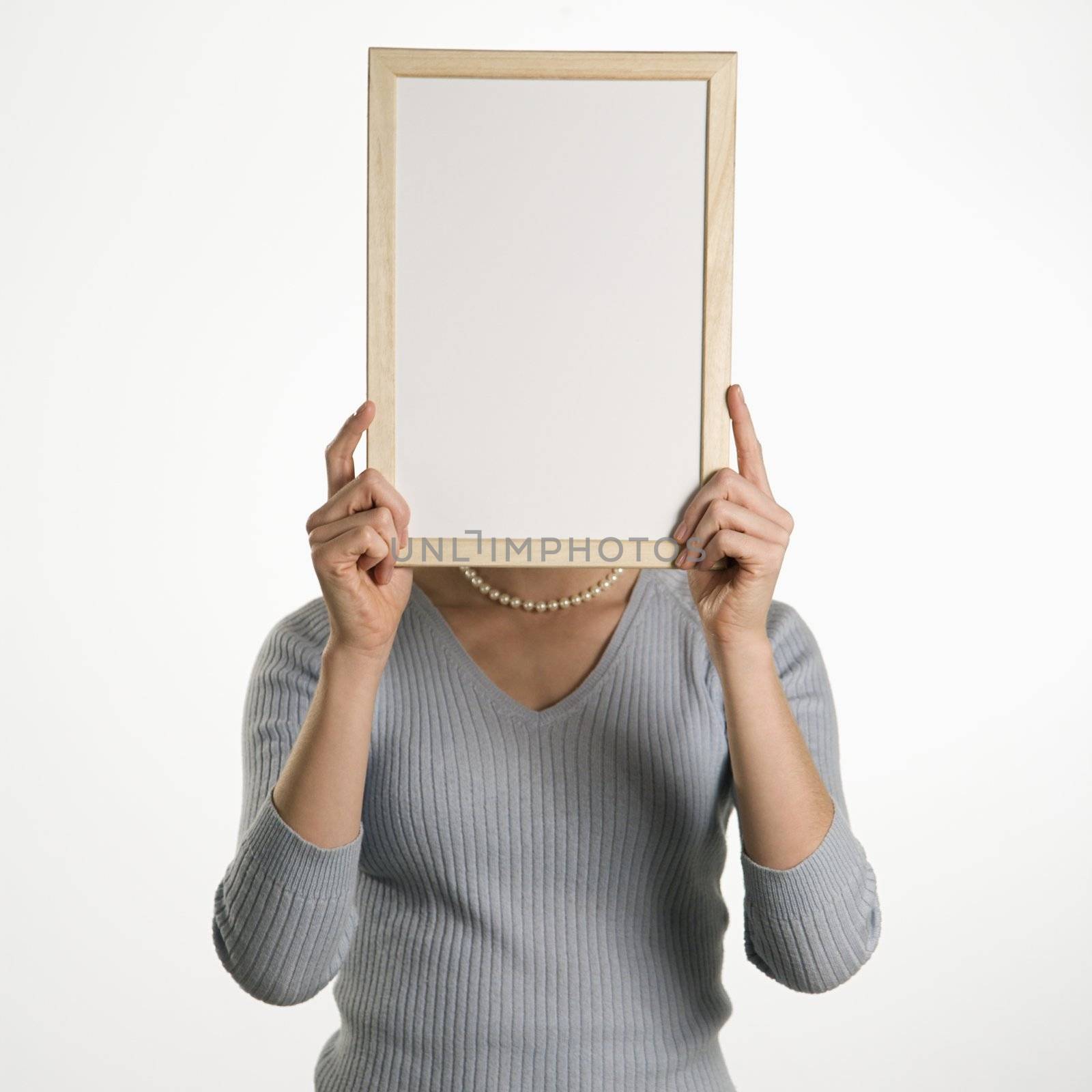Caucasian mid adult professional business woman holding up blank dry erase board in front of her face.