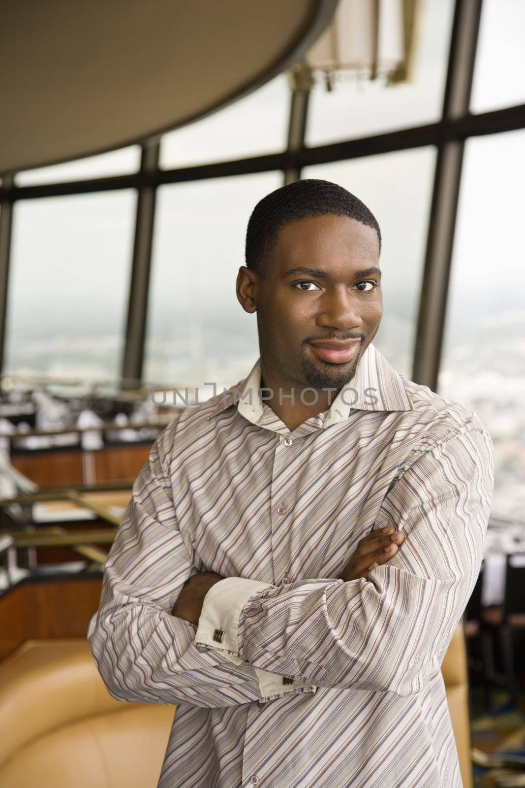 African American mid adult man smiling at viewer with arms crossed.