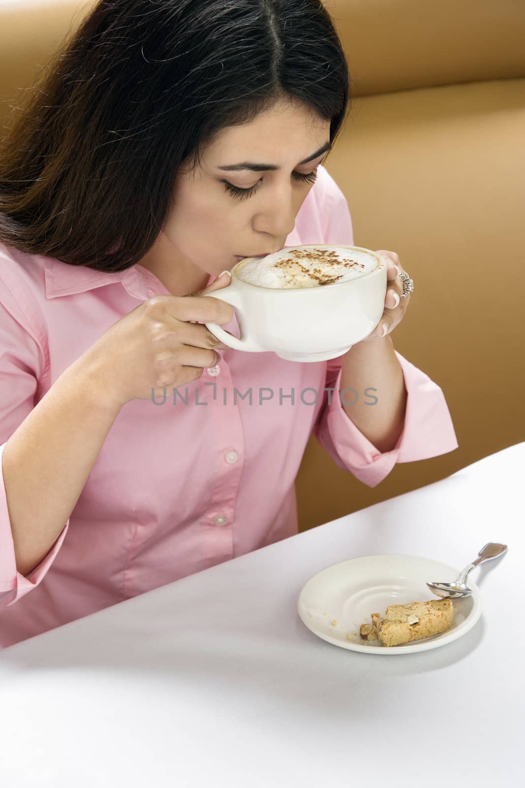 Attractive Hispanic woman drinking cappuccino.
