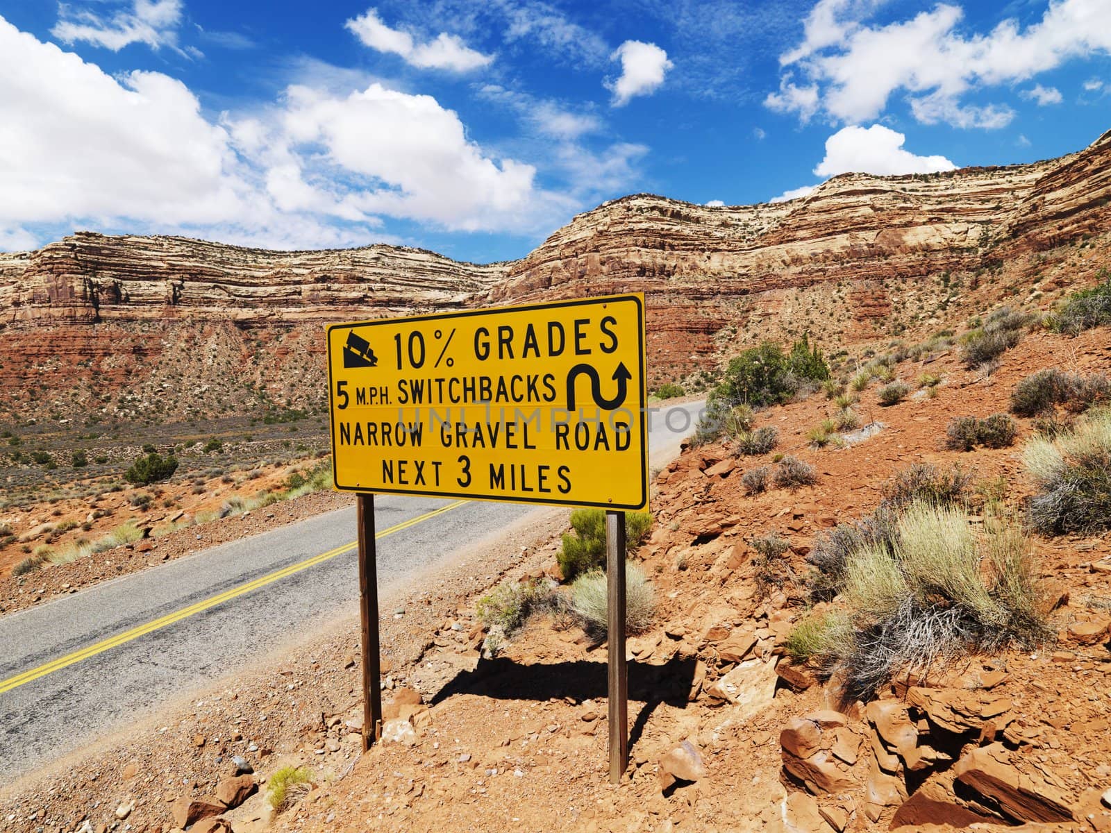 Road sign warning steep grade in mountainous Utah landscape.