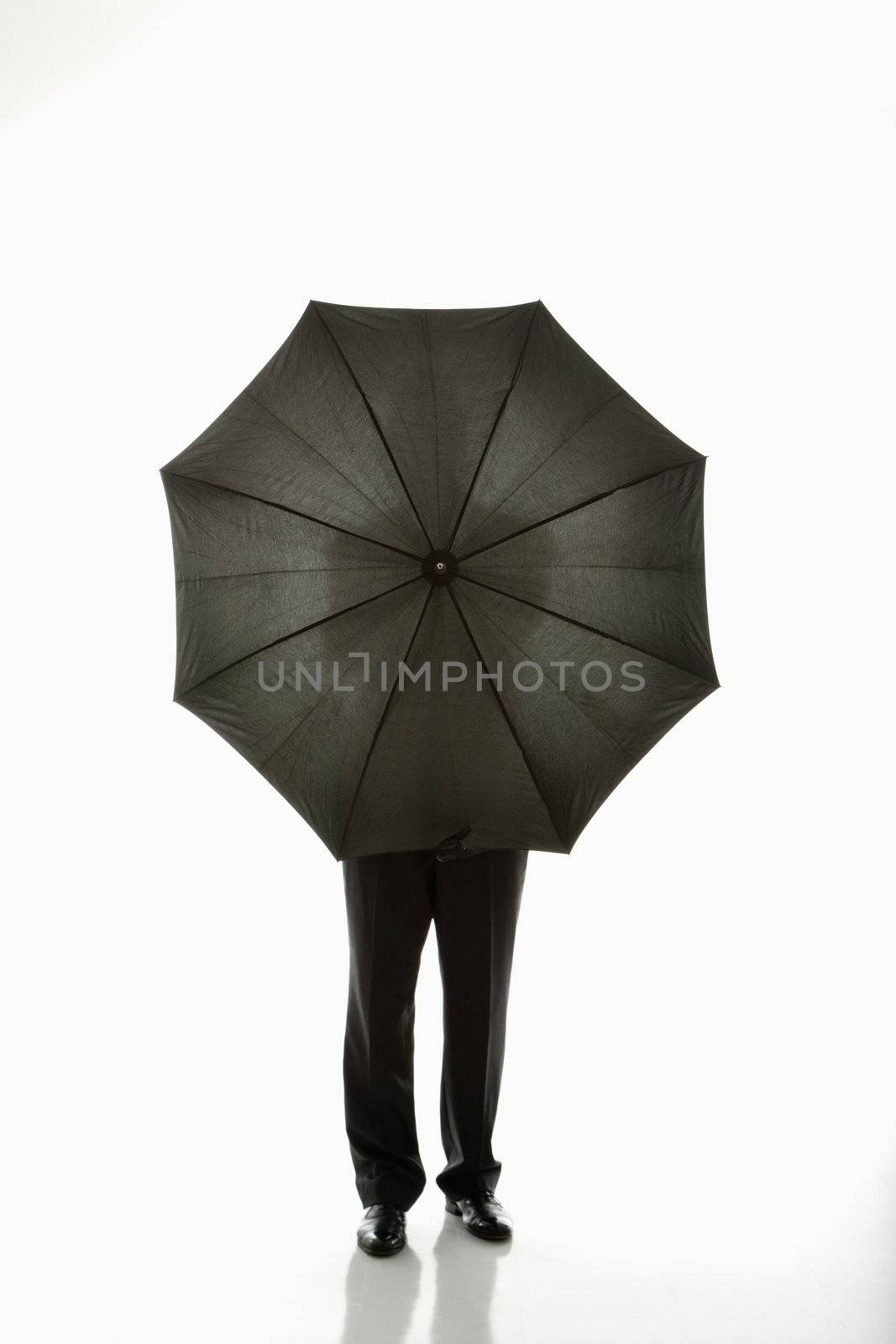 Businessman holding umbrella in front of body.