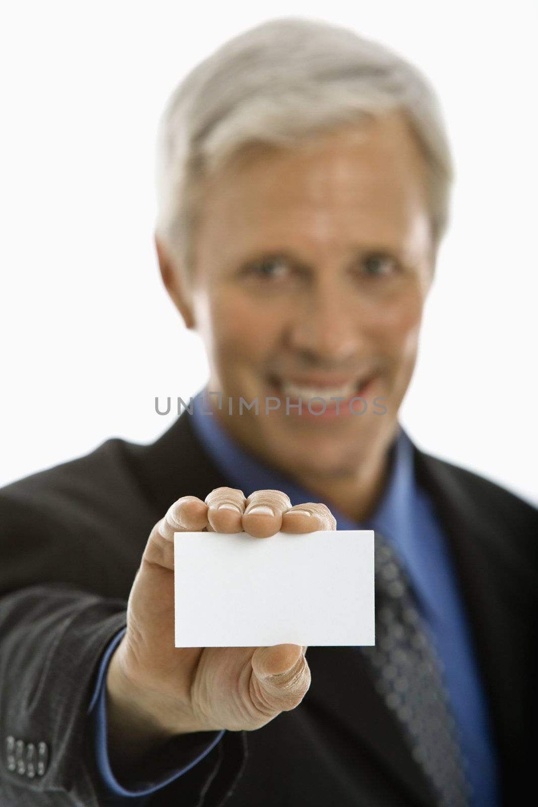 Caucasian middle aged man holding business card and smiling at viewer.