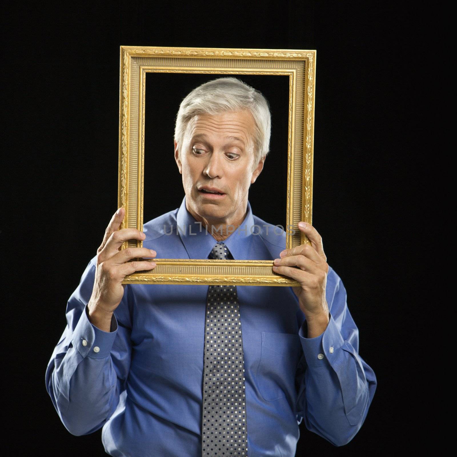 Man holding picture frame. by iofoto