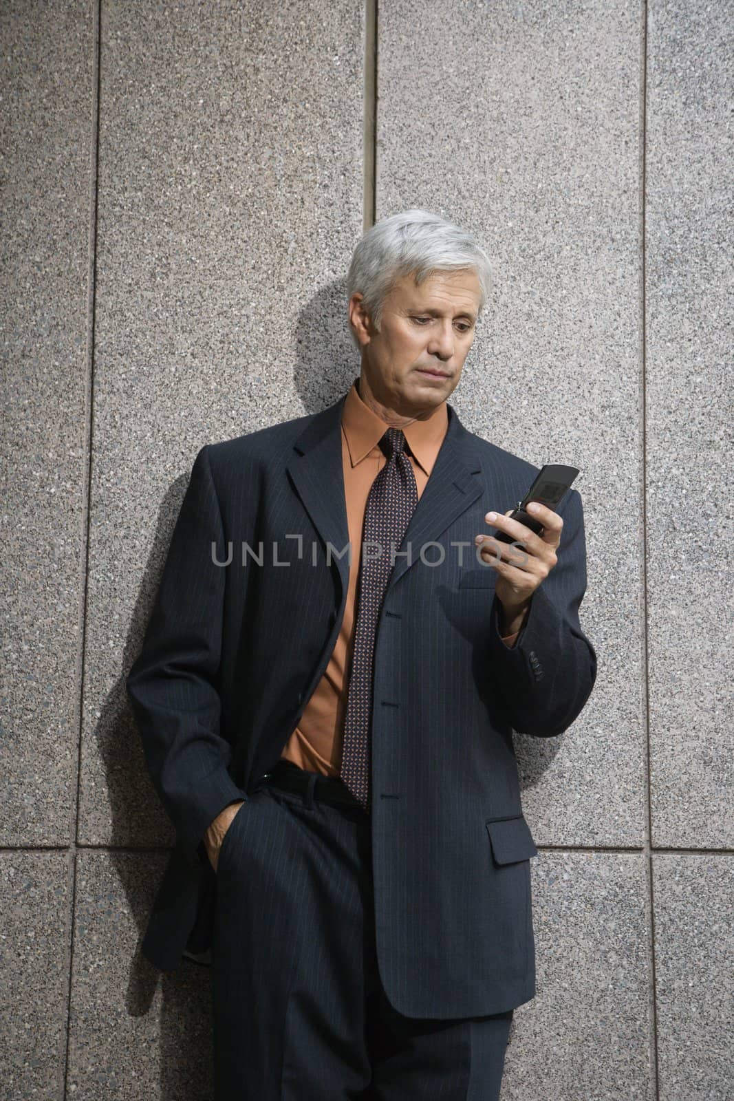 Caucasian middle aged businessman looking down at cell phone.