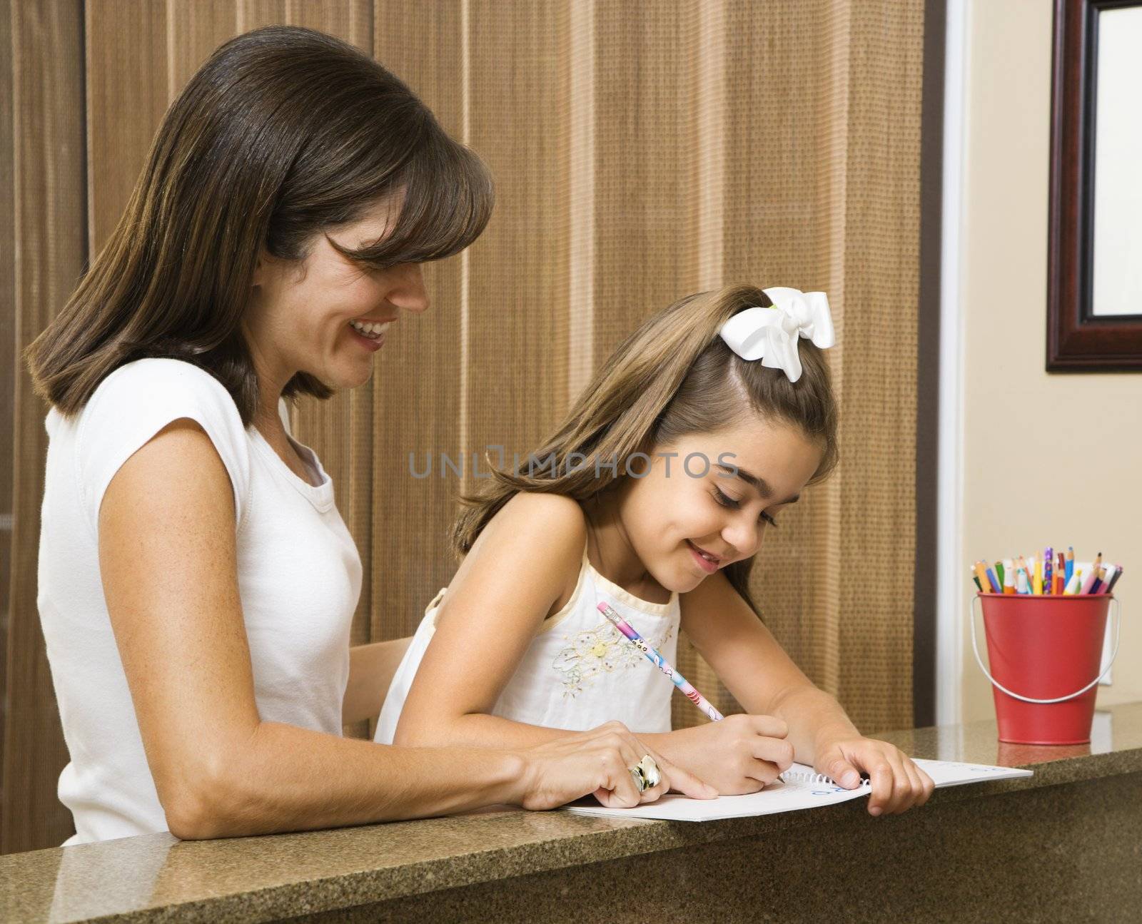 Hispanic mother helping daughter with homework.