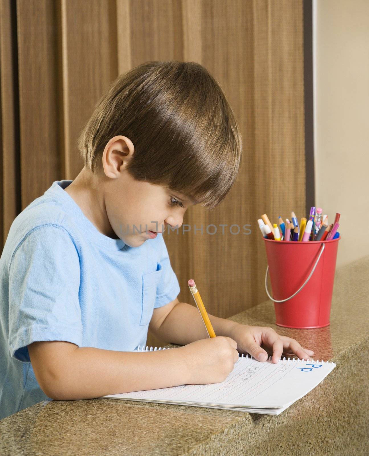 Side view of Hispanic boy concentrating on homework.