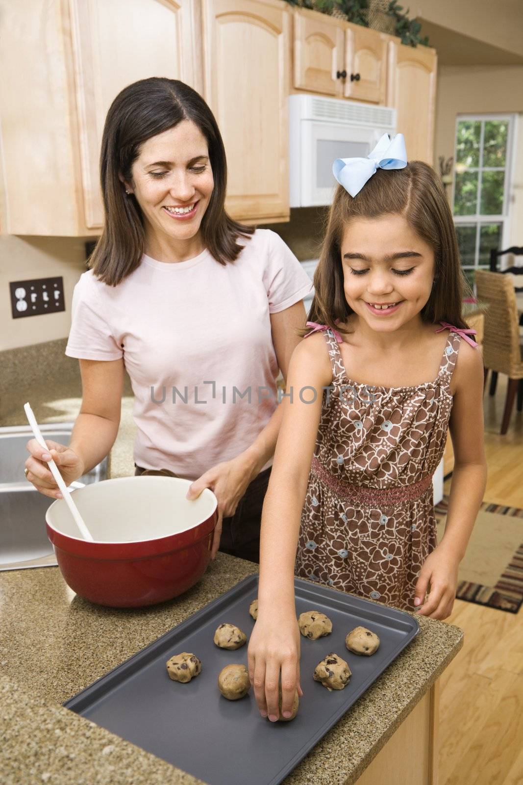 Hispanic mother and daughter in kitchen making cookies.
