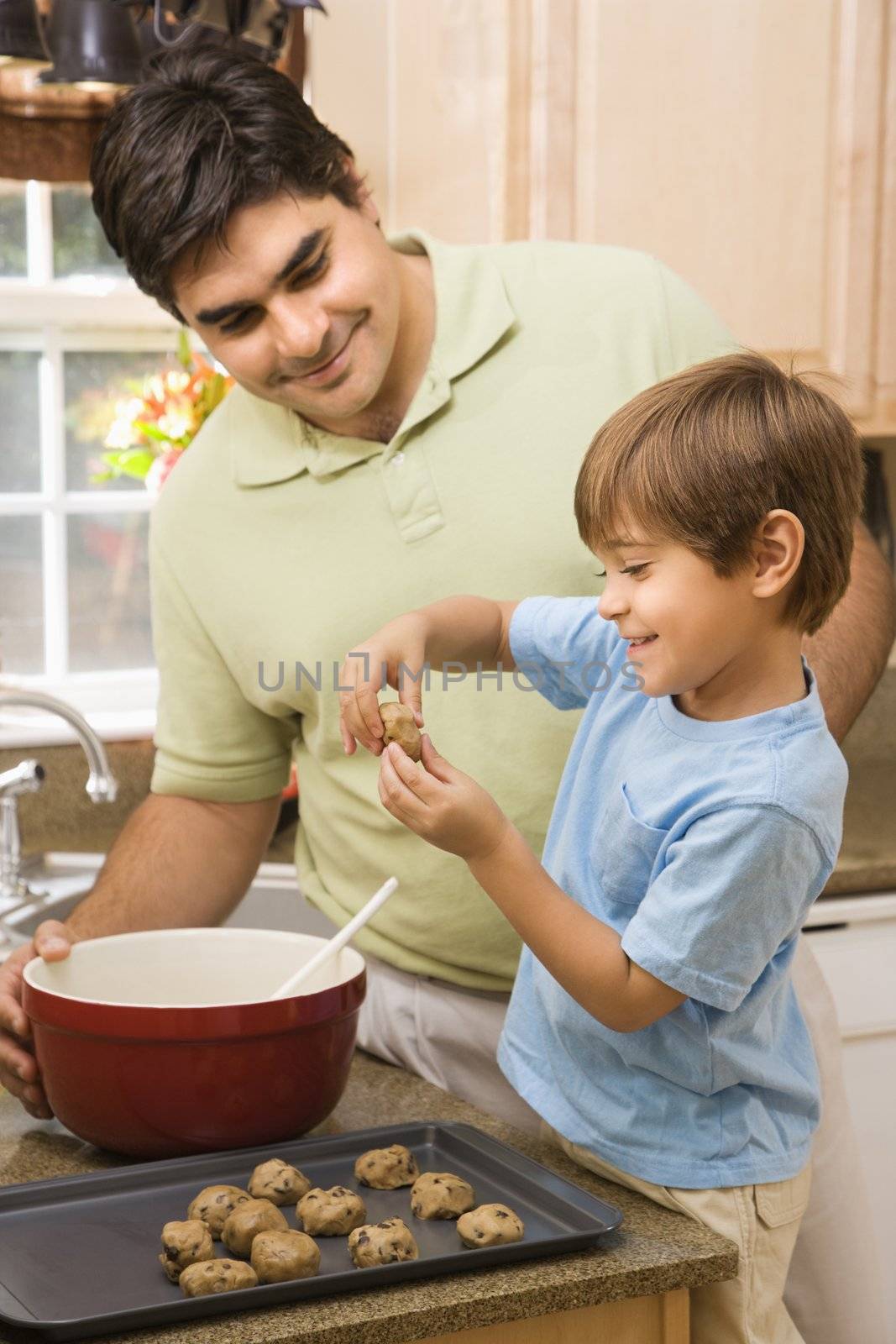 Hispanic father and son in kitchen making cookies.