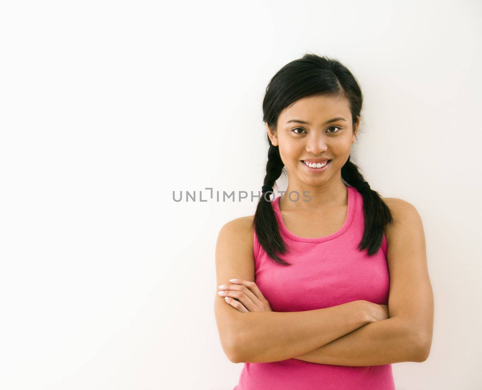 Portrait of young woman standing with arms crossed smiling.