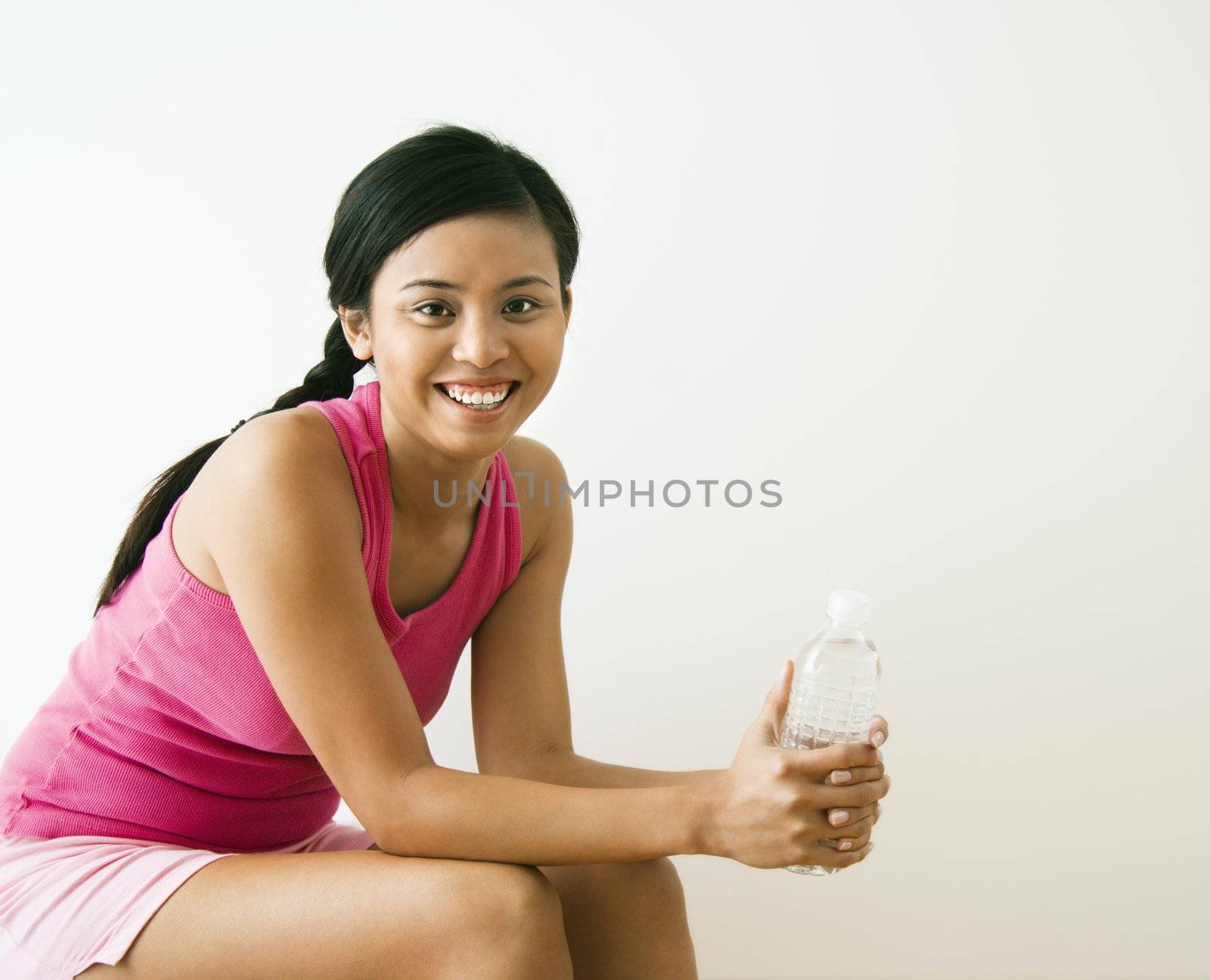 Portrait of smiling young Asian woman holding bottle of water.