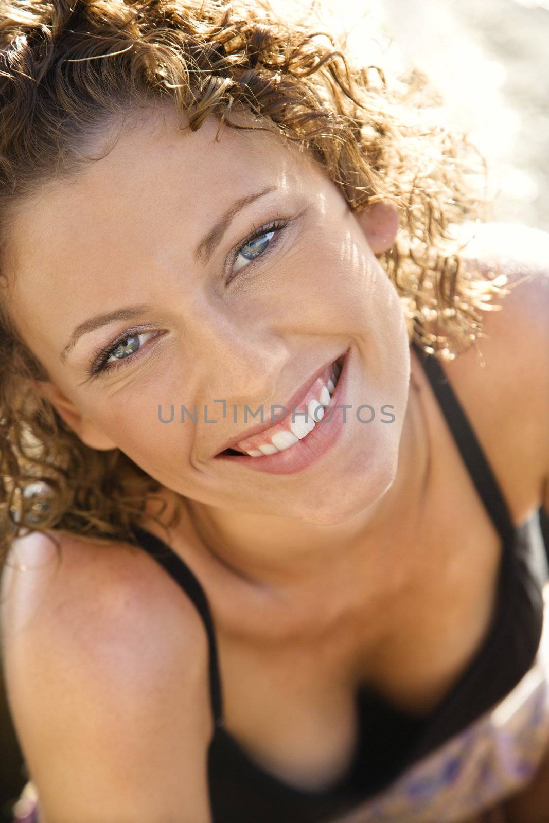 Portrait of smiling Caucasian young adult female looking up at viewer.