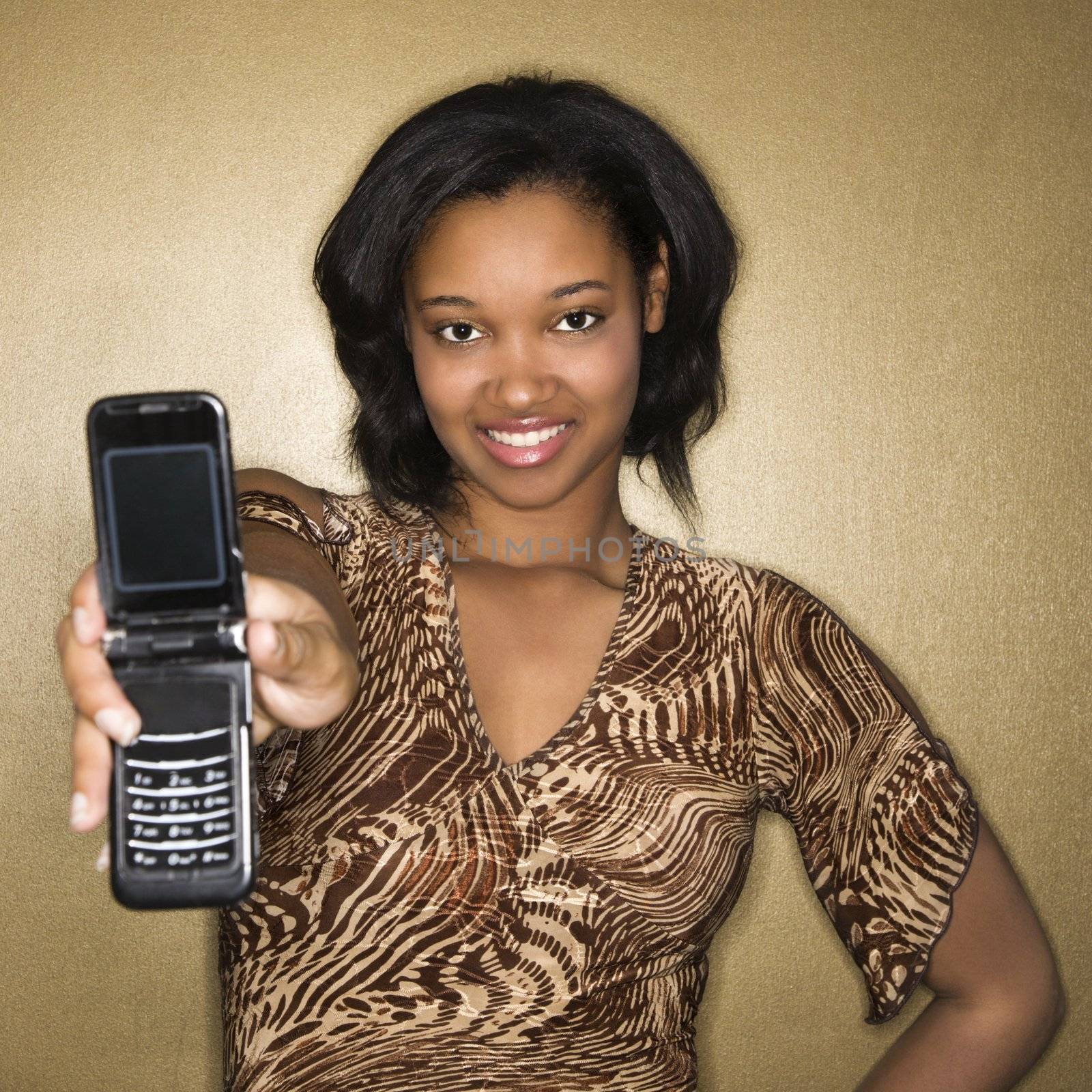 Young African-American young woman holding cellphone out to viewer.