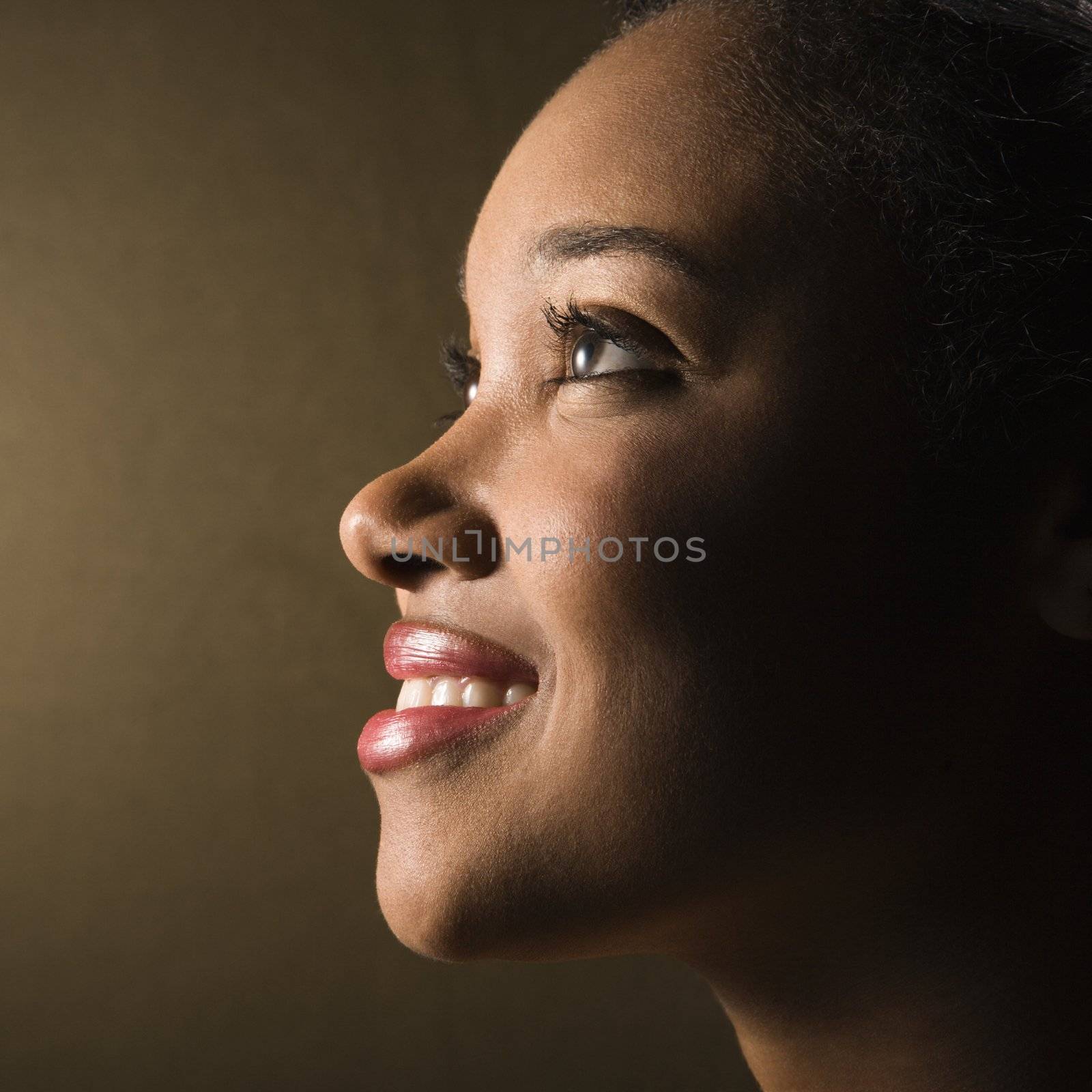 Profile of smiling young woman. by iofoto