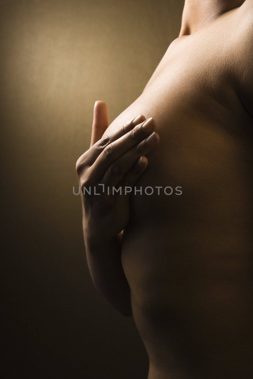 Young adult African-American female giving self breast exam.