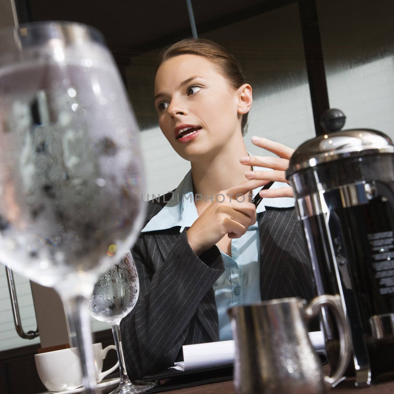 Caucasian businesswoman sitting at table with coffee and beverages.