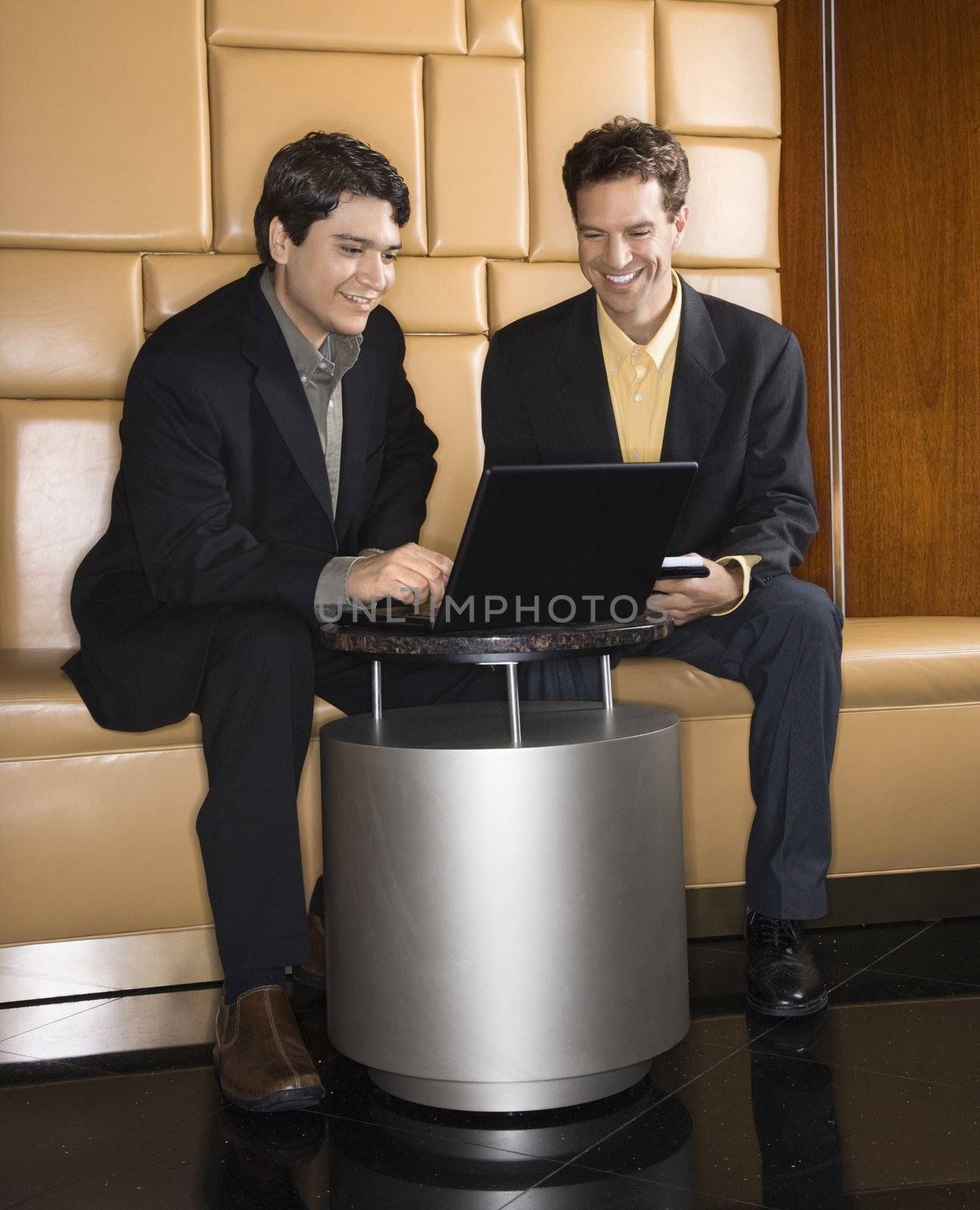 Businessmen talking and viewing laptop computer.