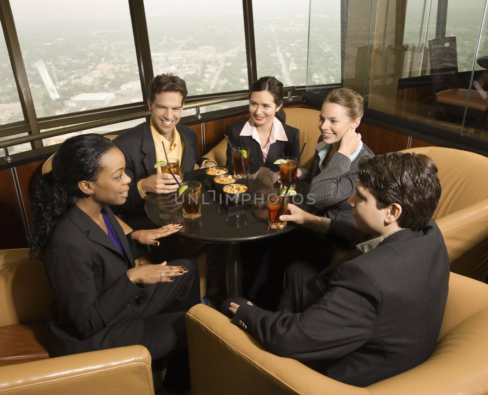 Ethnically diverse businesspeople sitting at table in restaurant talking.