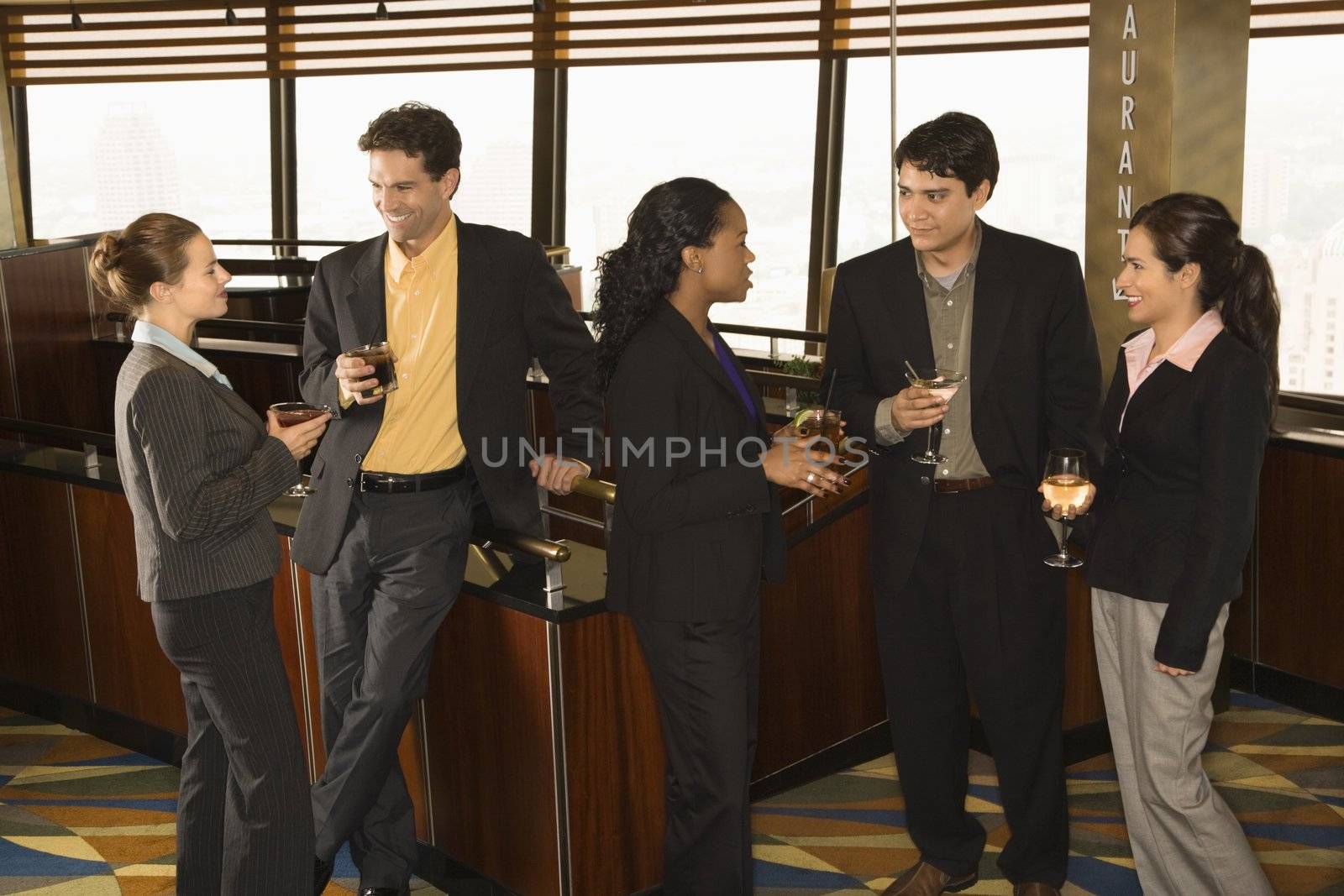Ethnically diverse group of businesspeople in bar drinking and conversing.