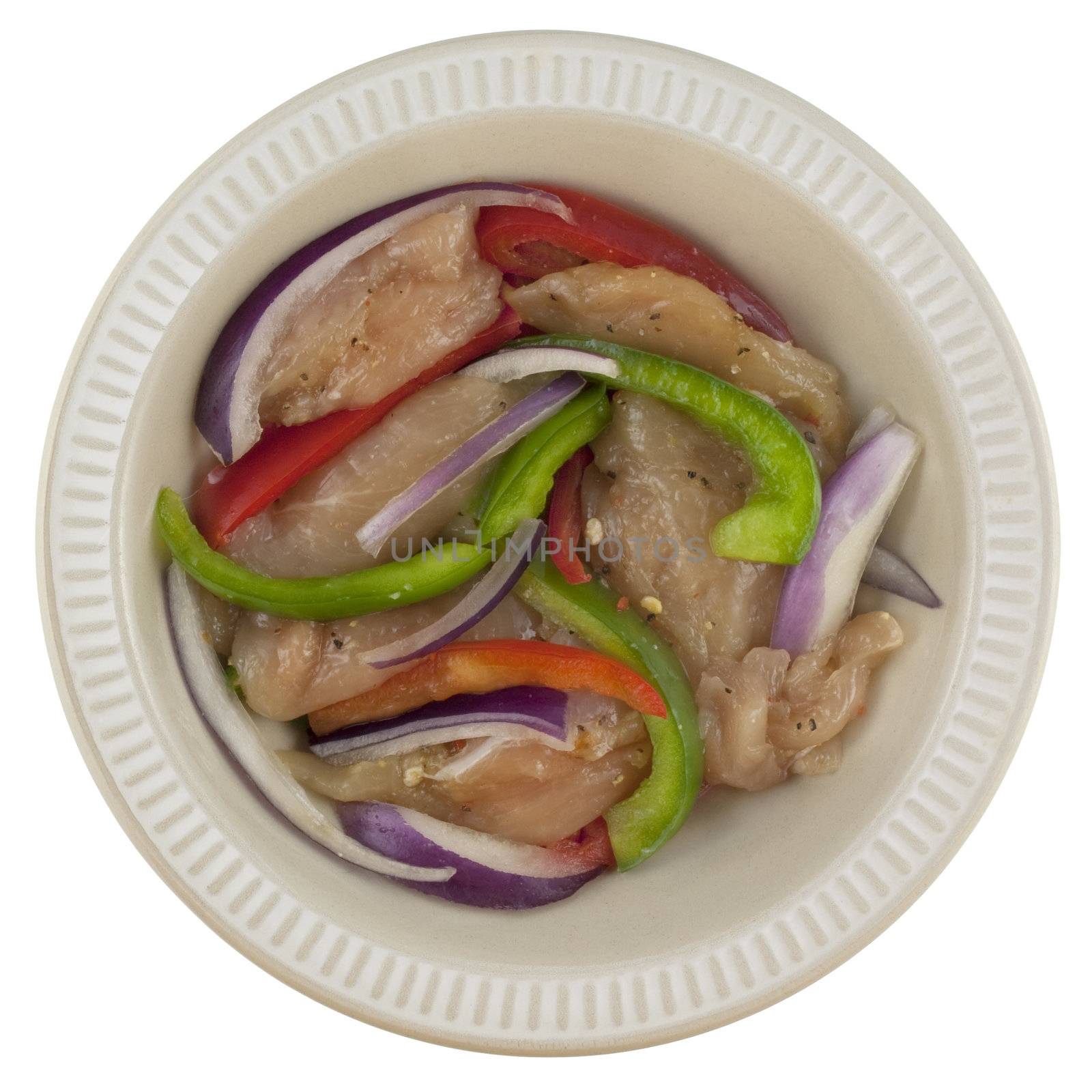 ready to grill raw marinated chicken fajita with onion, red and green bell pepper in a round bowl isolated on white