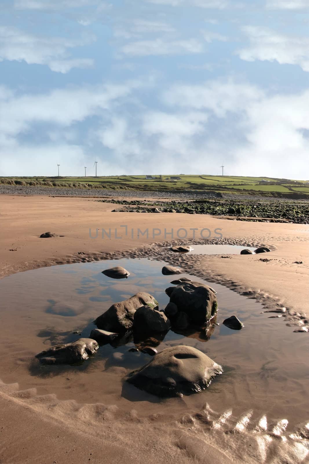 rock pool on beale beach co kerry ireland on a cold winters morning with turbines in the background