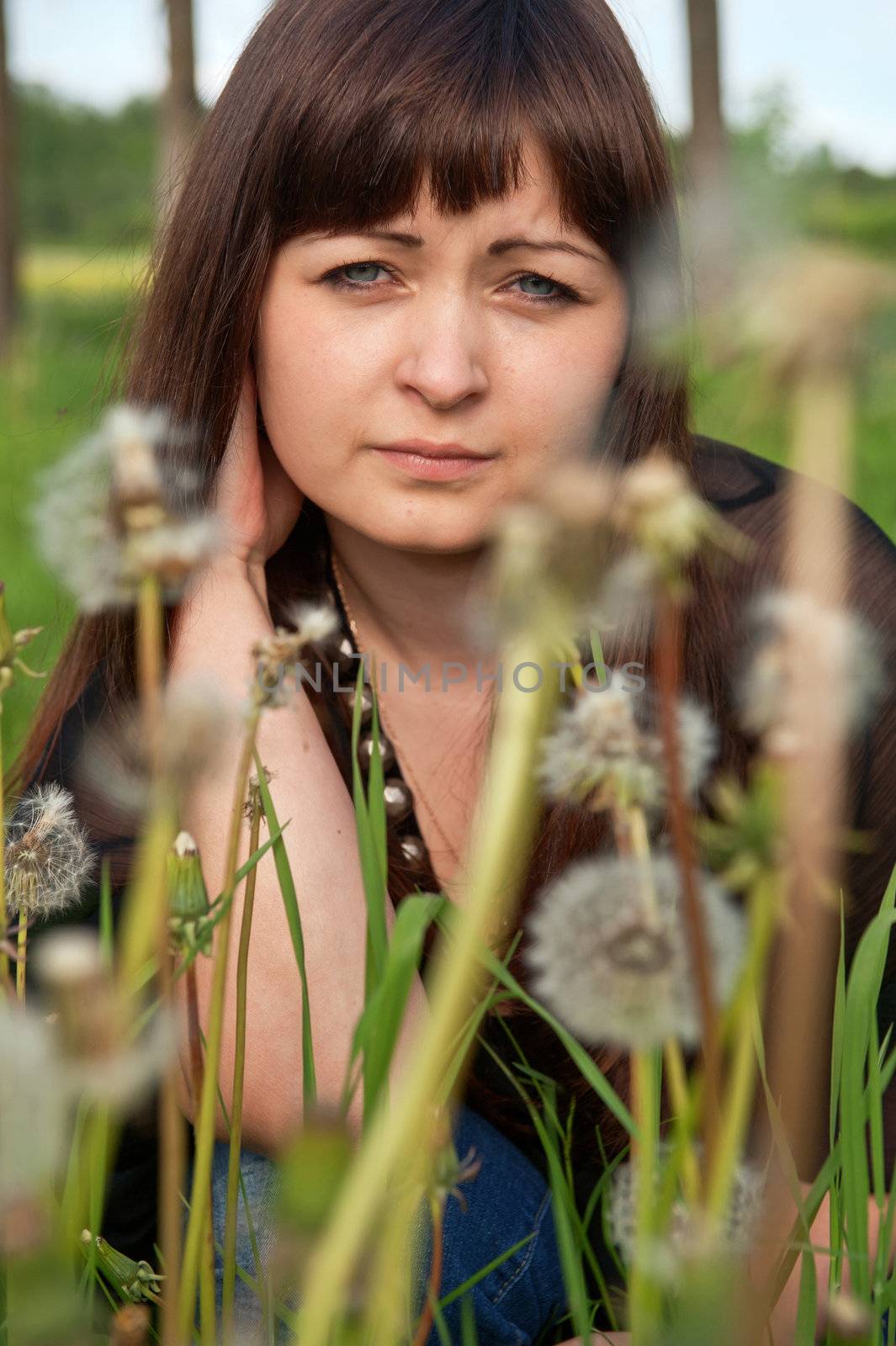 Portrait of young beautiful woman in meadow of dandelions.