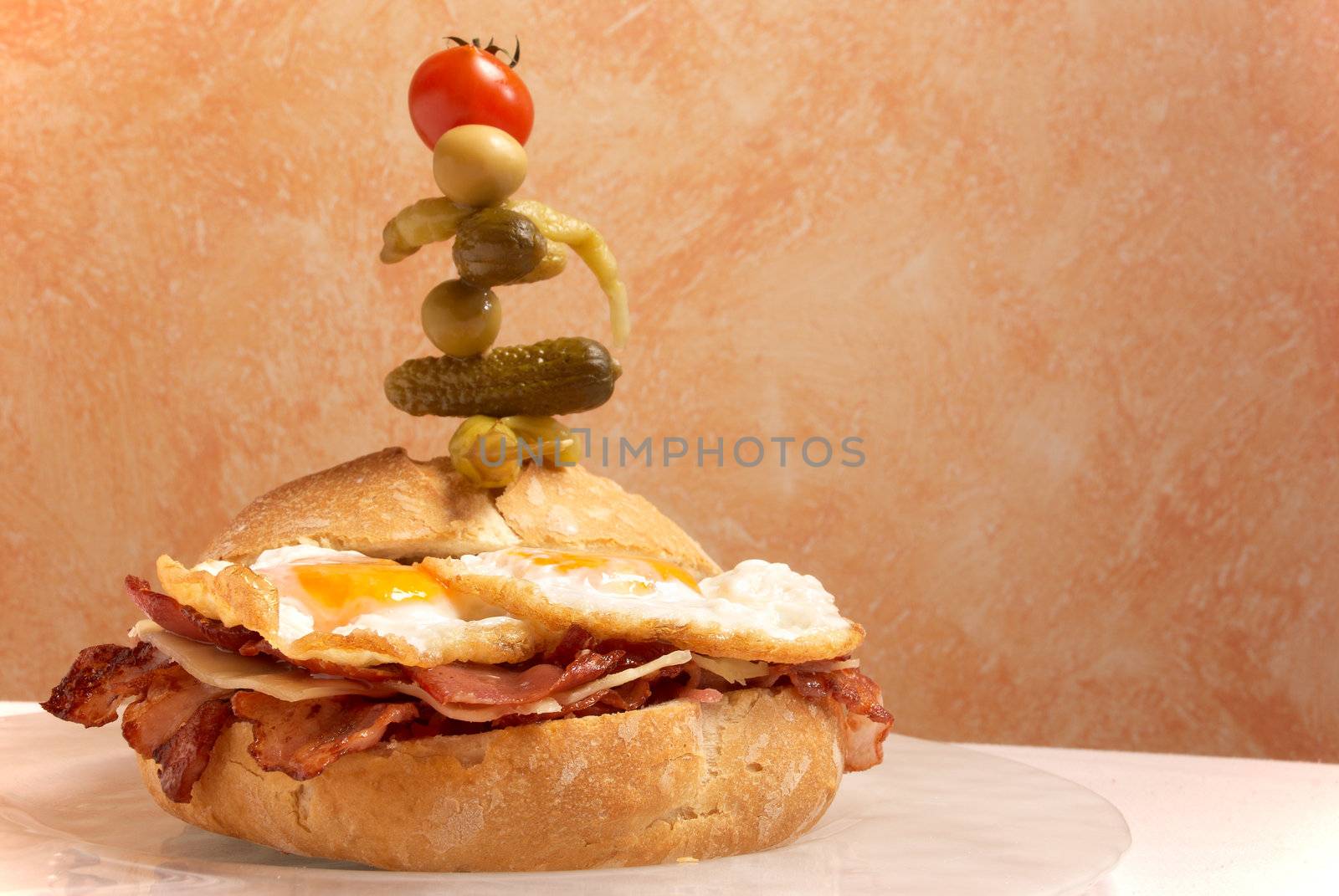 Supersized bacon, cheese and eggs sandwich decorated with pickles