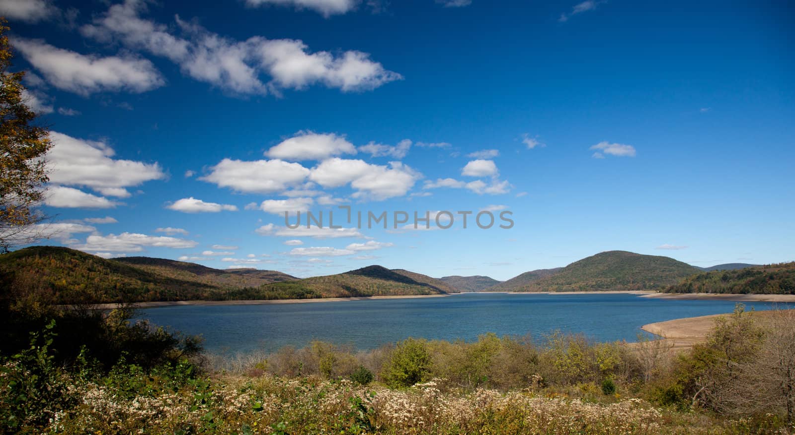 Autumn scene at Cannonsville Reservoir in New York as leaves are reflected in calm river