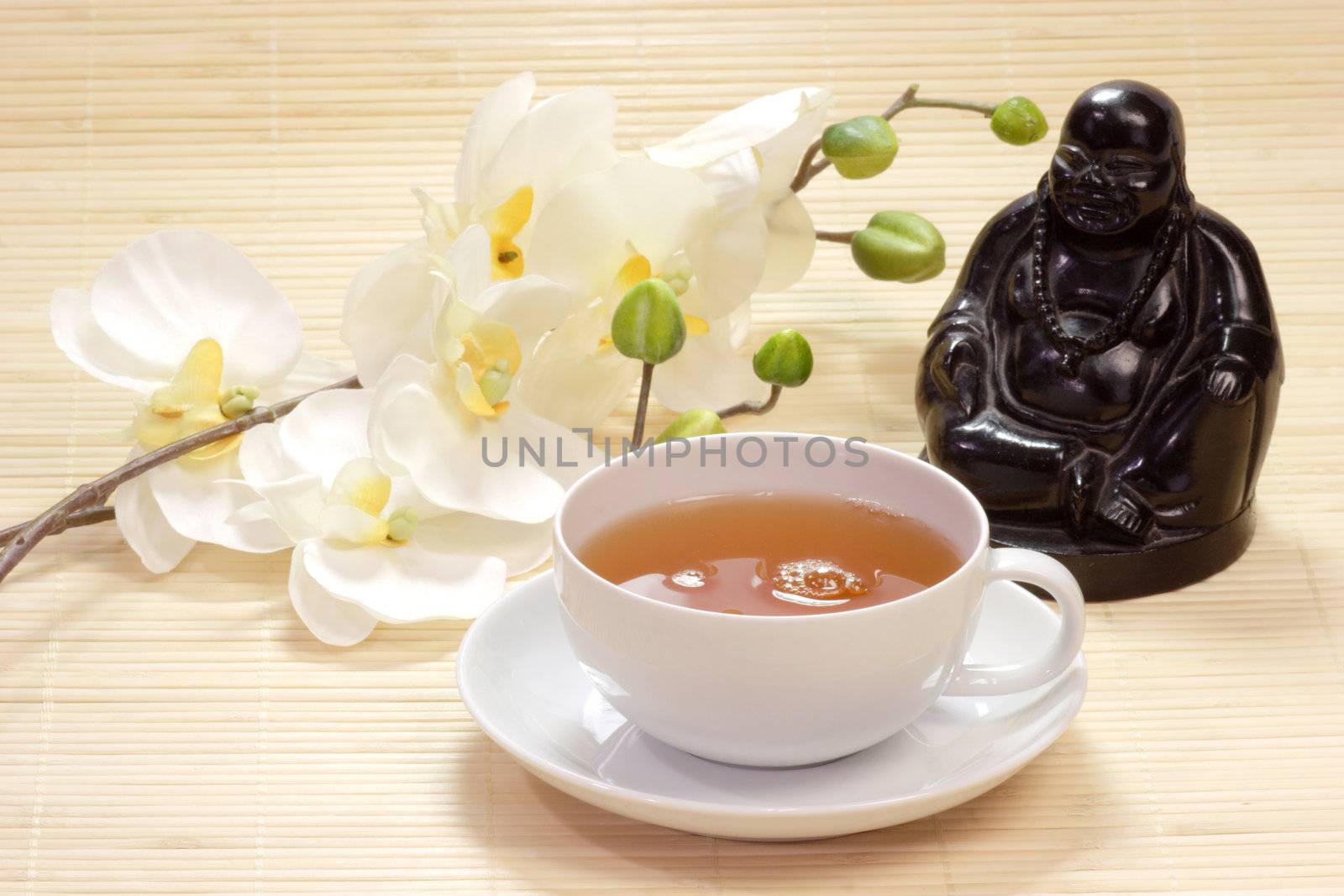 Gr�ner Tee in einer Tasse mit Buddhafigur und wei�en Bl�ten als Dekoration