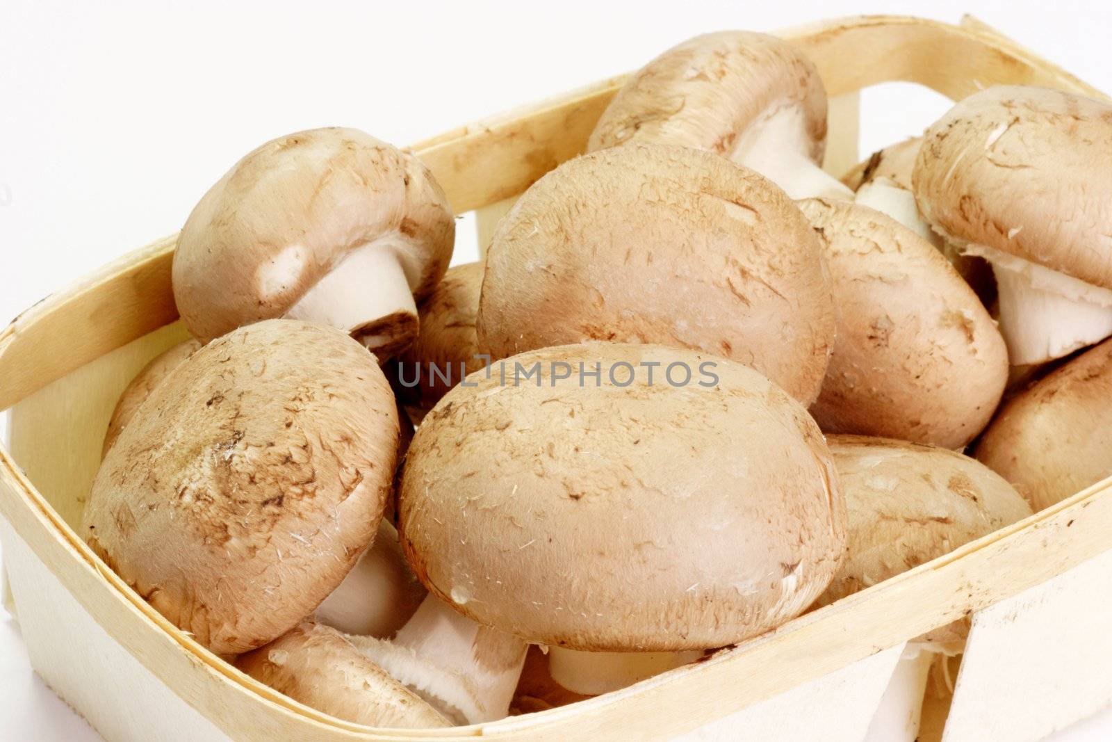 Closeup of fresh brown mushrooms in a basket over white background
