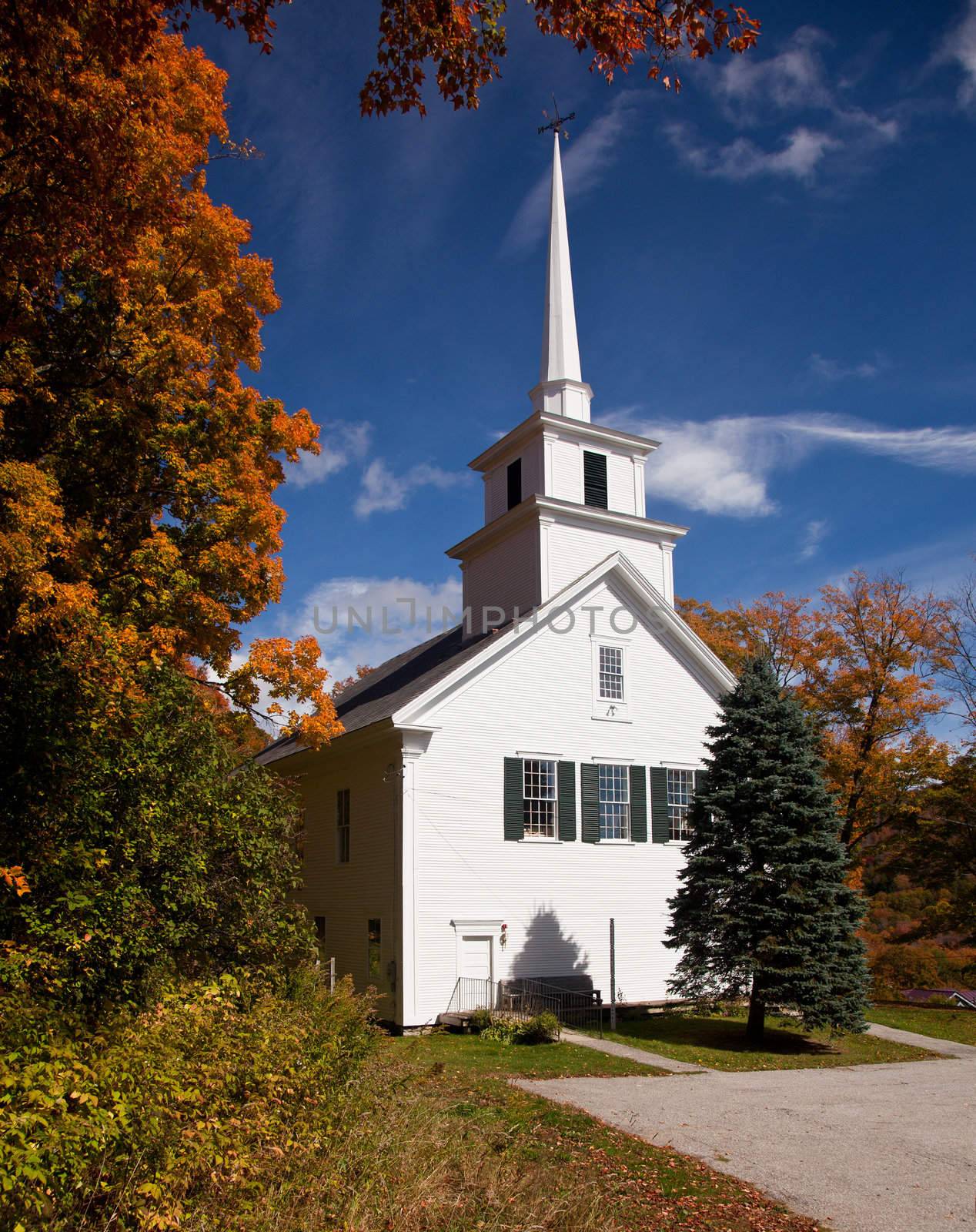 Autumnal shot of the typical Vermont church in fall as the bright trees turn orange and red