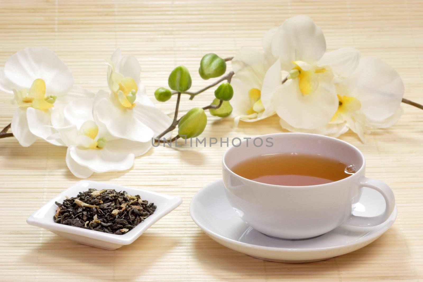 Cup of jasmine tea wih tea leaves in a bowl